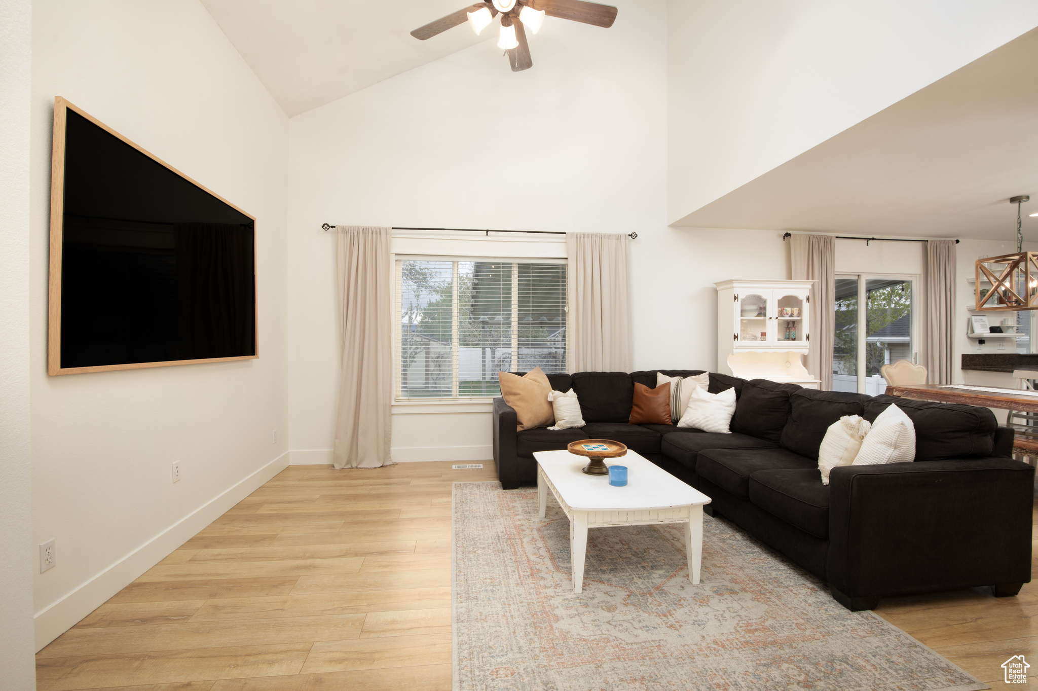 Living room featuring high vaulted ceiling, light hardwood / wood-style floors, plenty of natural light, and ceiling fan