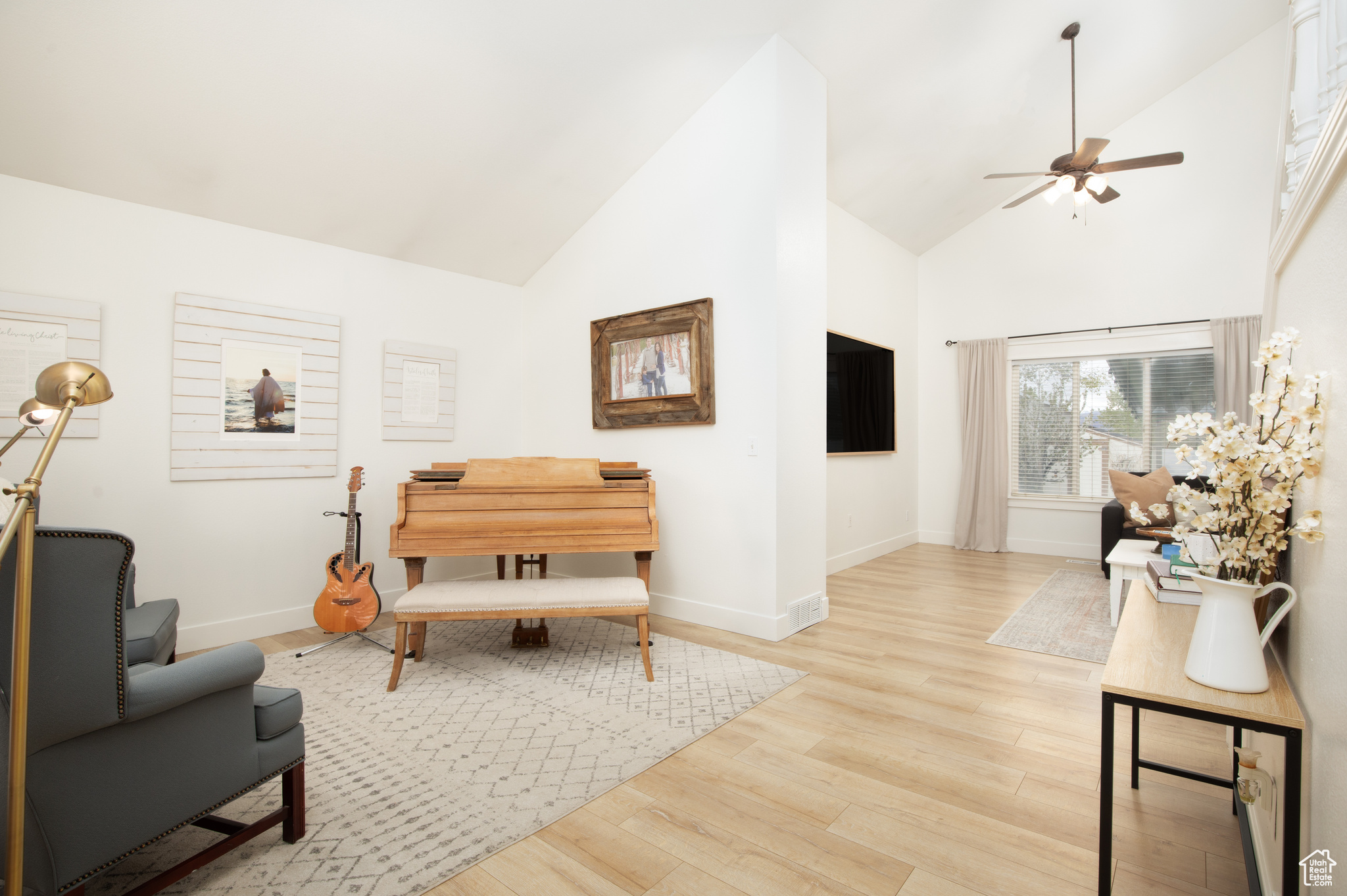 Living room featuring light hardwood / wood-style flooring, high vaulted ceiling, and ceiling fan
