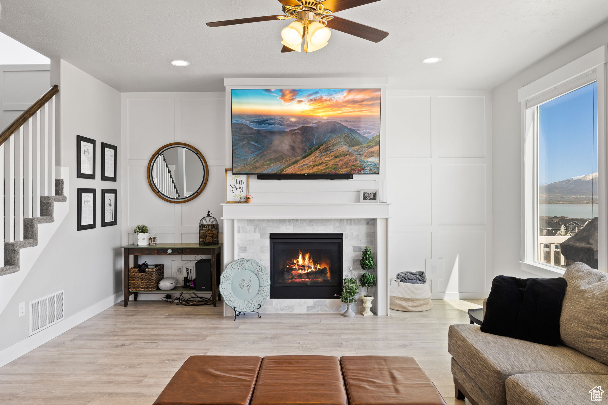 Living room with light hardwood / wood-style flooring, ceiling fan, and a tile fireplace