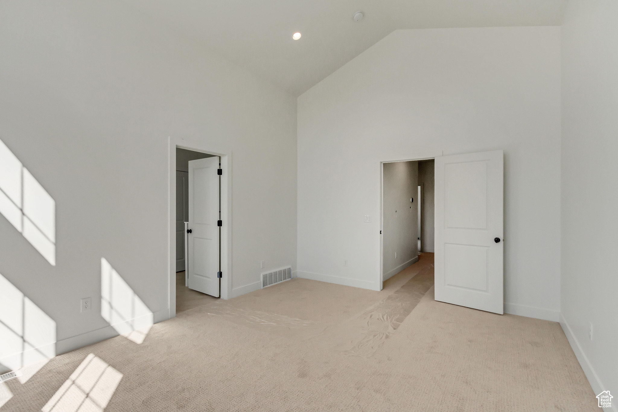 Unfurnished room featuring high vaulted ceiling and light carpet