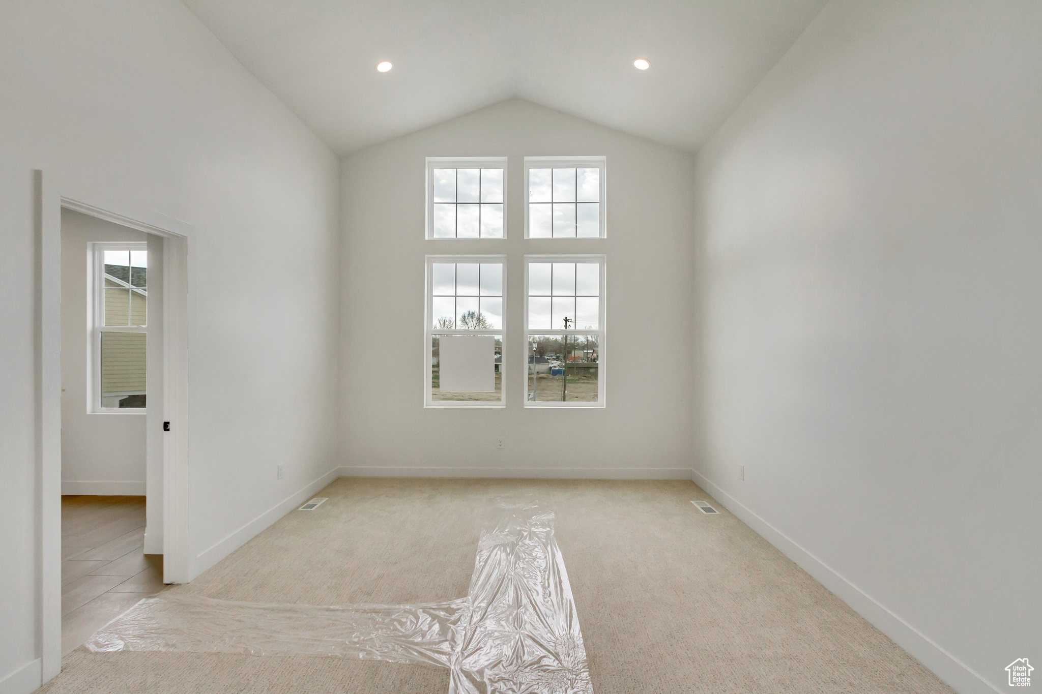 Unfurnished room with light carpet and lofted ceiling