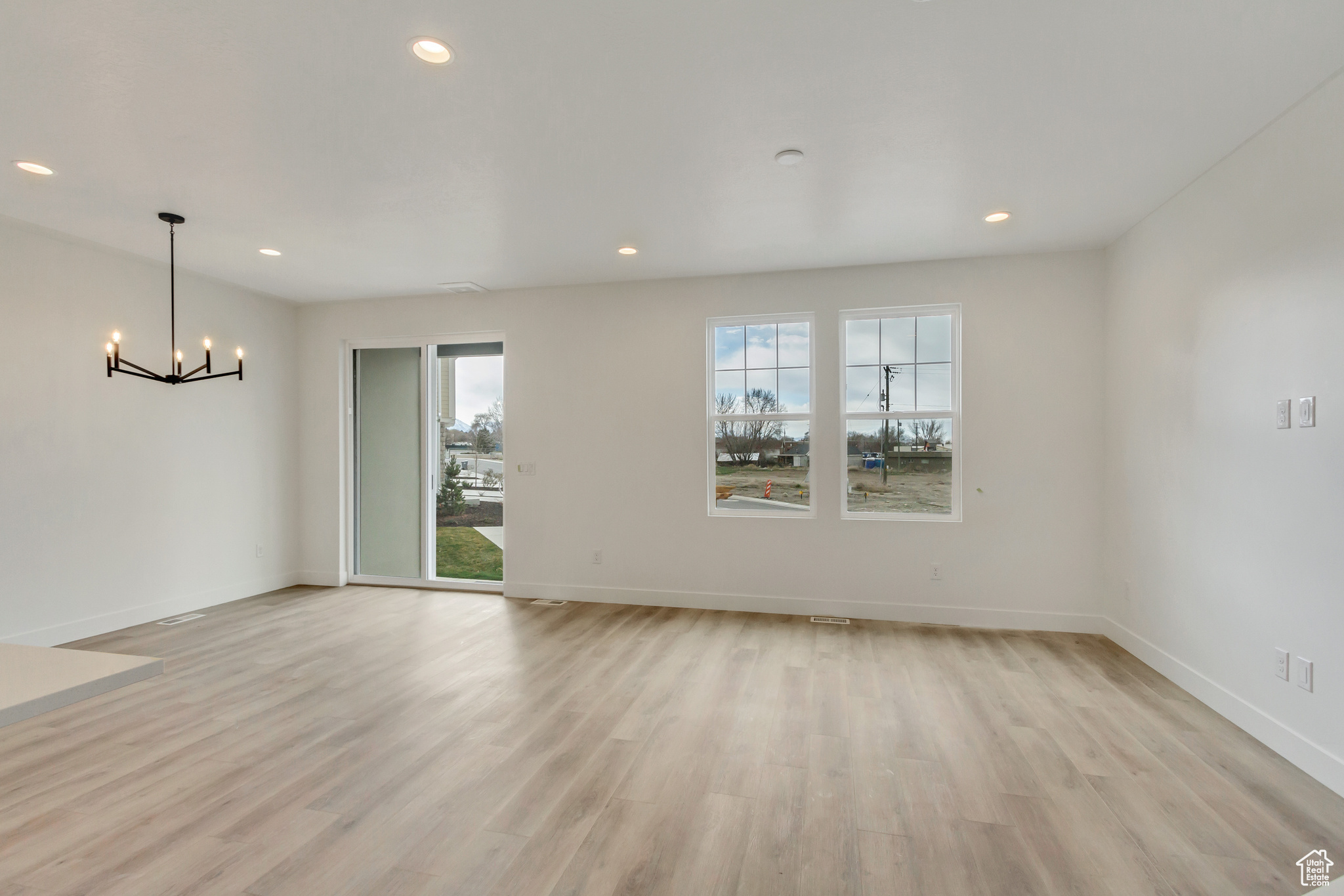 Unfurnished room featuring a chandelier, a healthy amount of sunlight, and light hardwood / wood-style floors