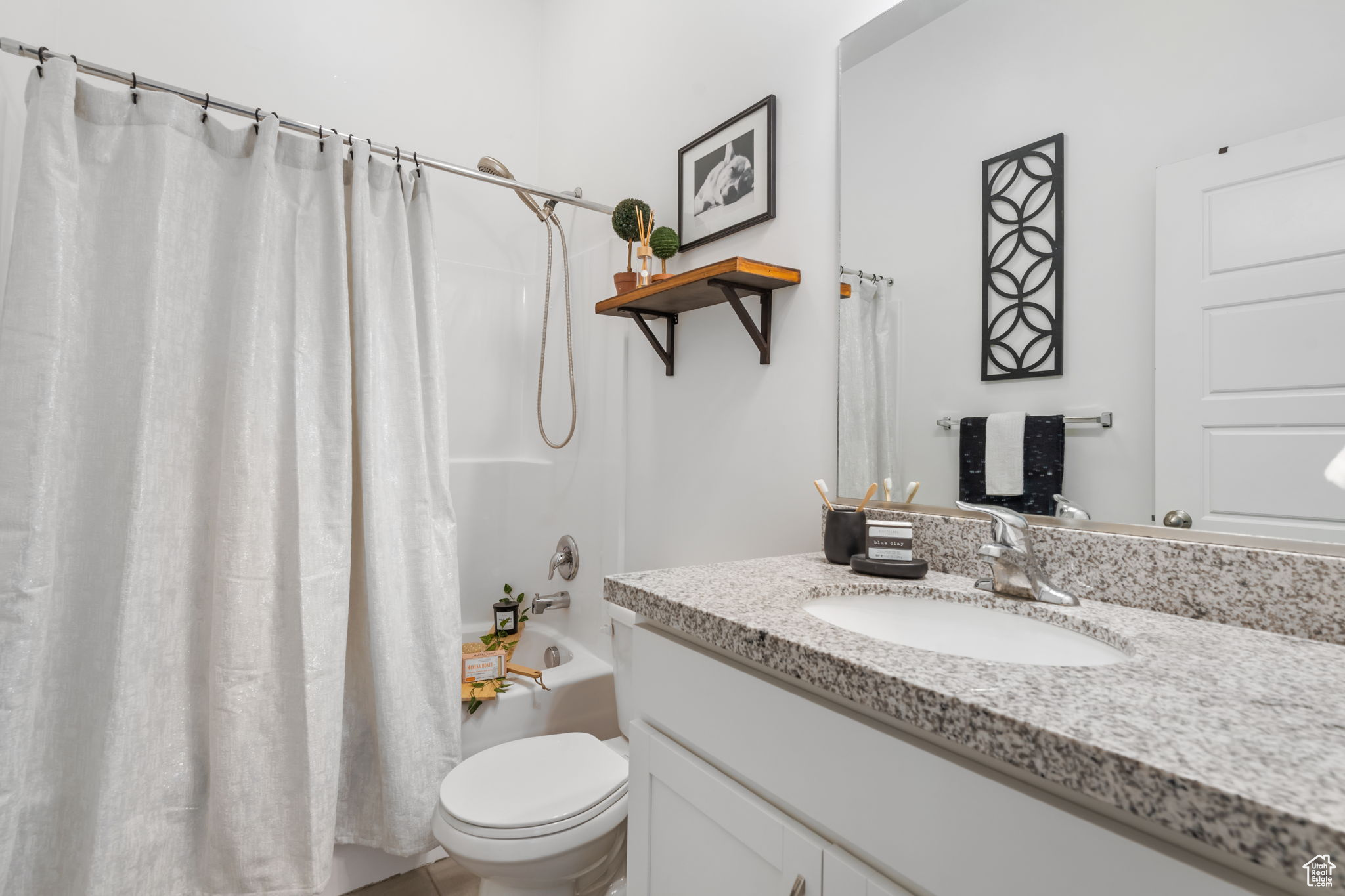 Full bathroom featuring vanity with extensive cabinet space, toilet, and shower / bath combo with shower curtain