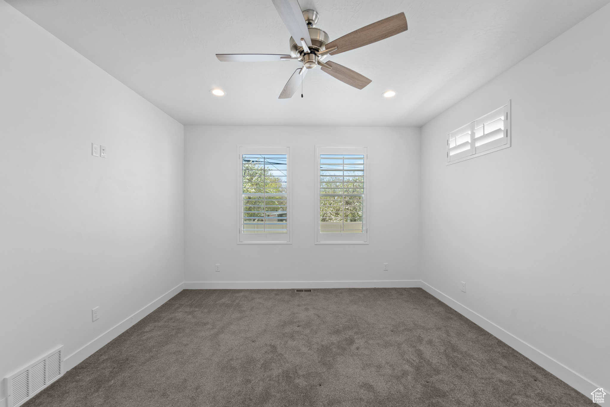 Spare room featuring dark colored carpet and ceiling fan