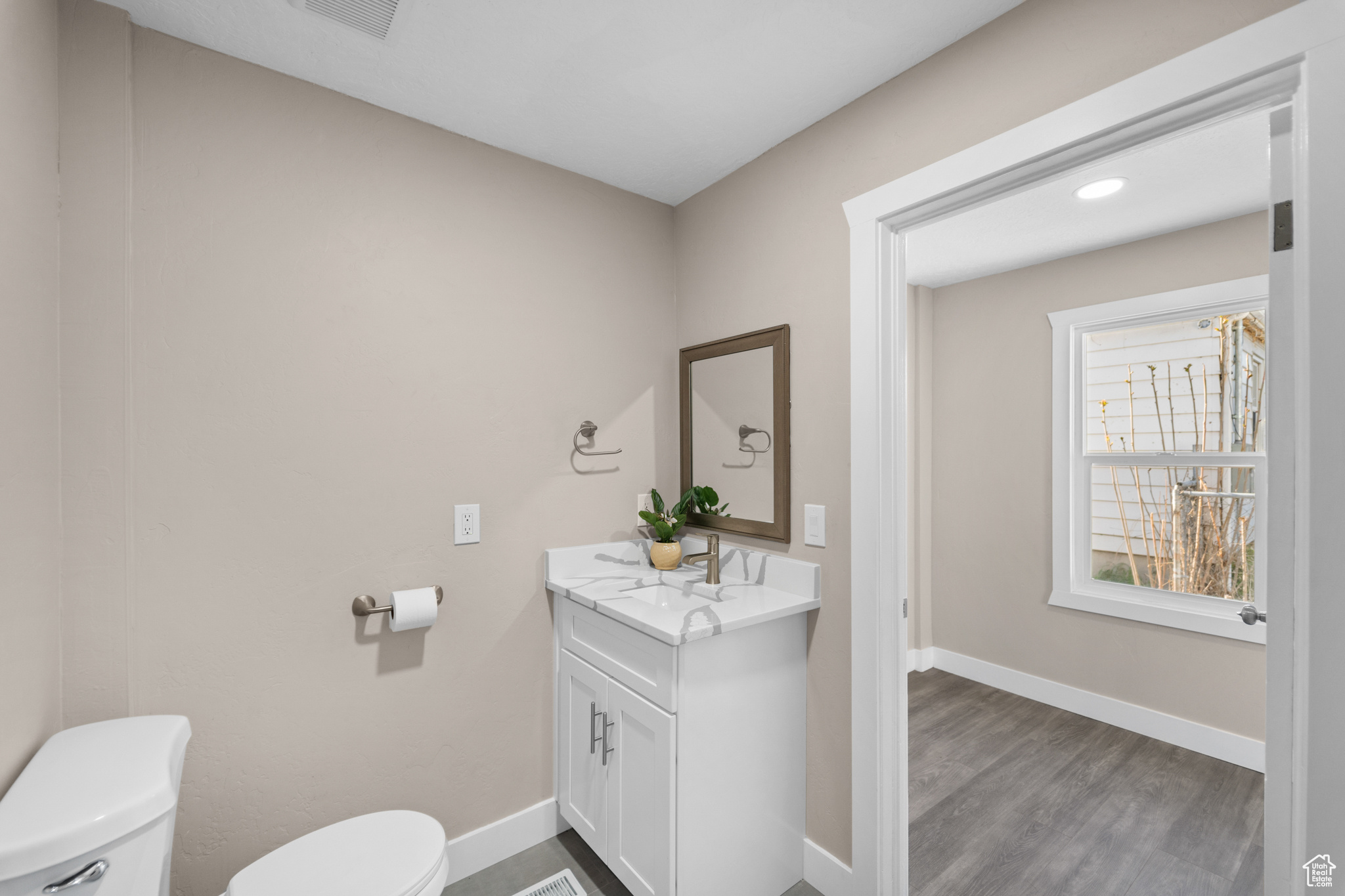 Bathroom with hardwood / wood-style flooring, vanity, and toilet