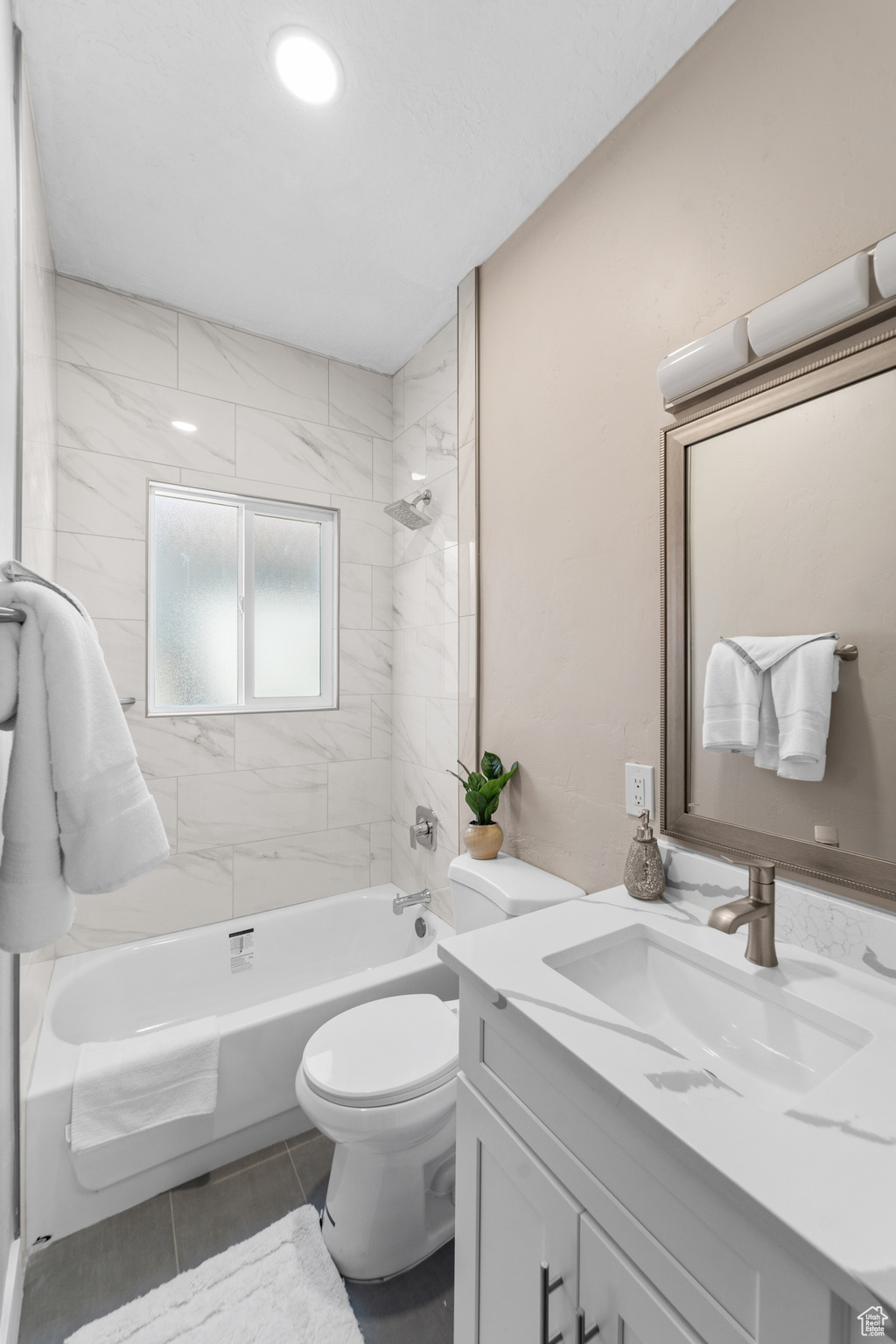 Full bathroom featuring tiled shower / bath combo, vanity, toilet, and tile flooring