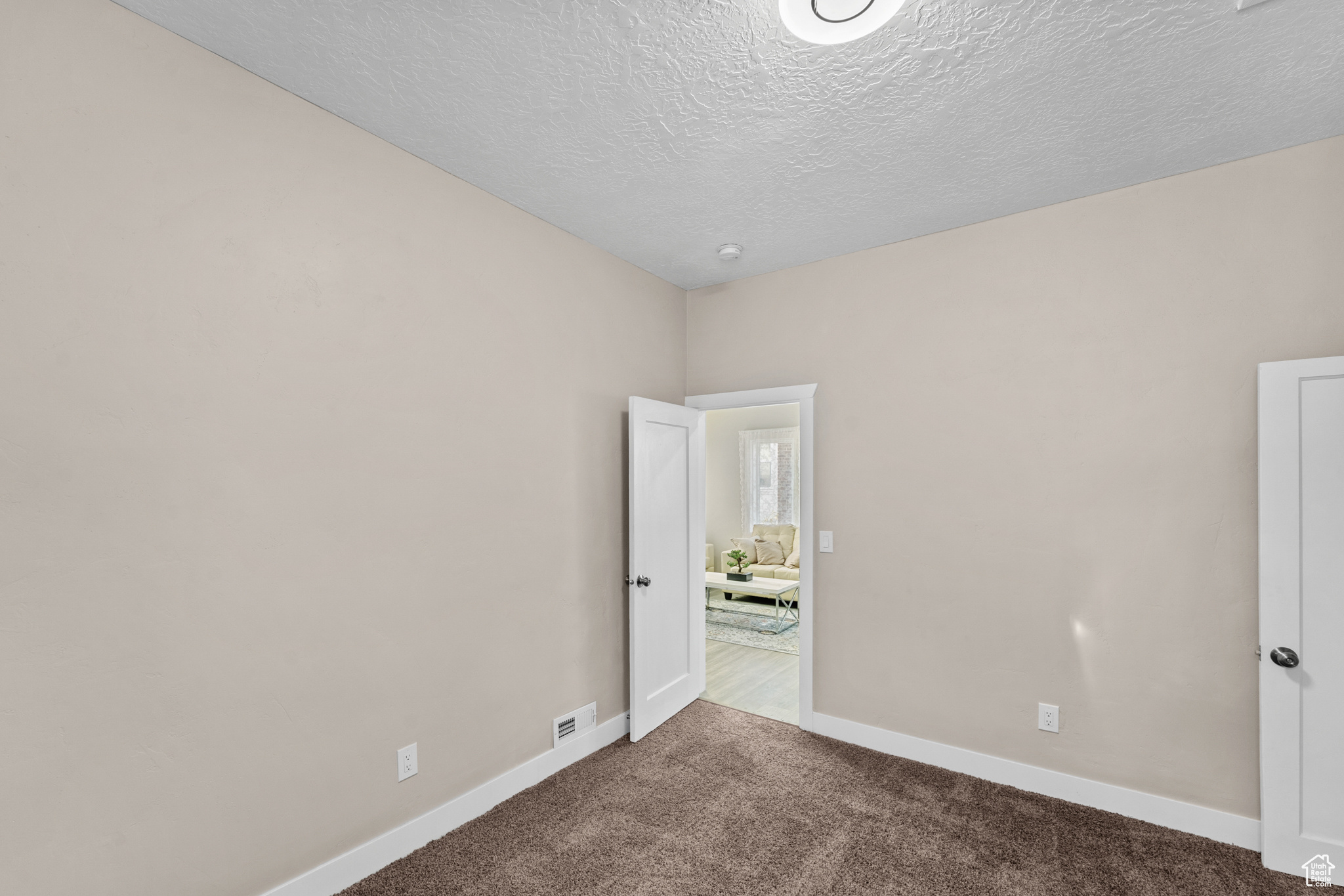 Unfurnished bedroom with dark carpet and a textured ceiling