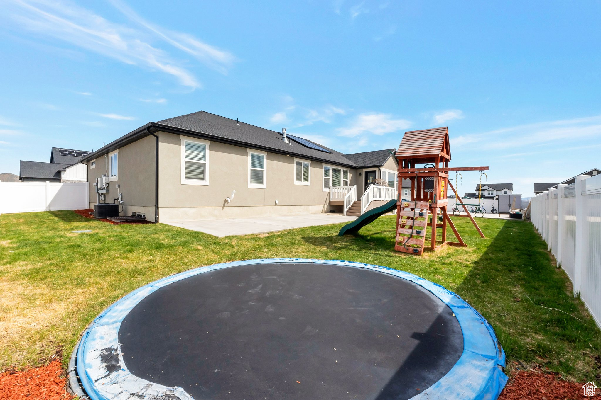 Rear view of property featuring a playground, central AC unit, and a lawn