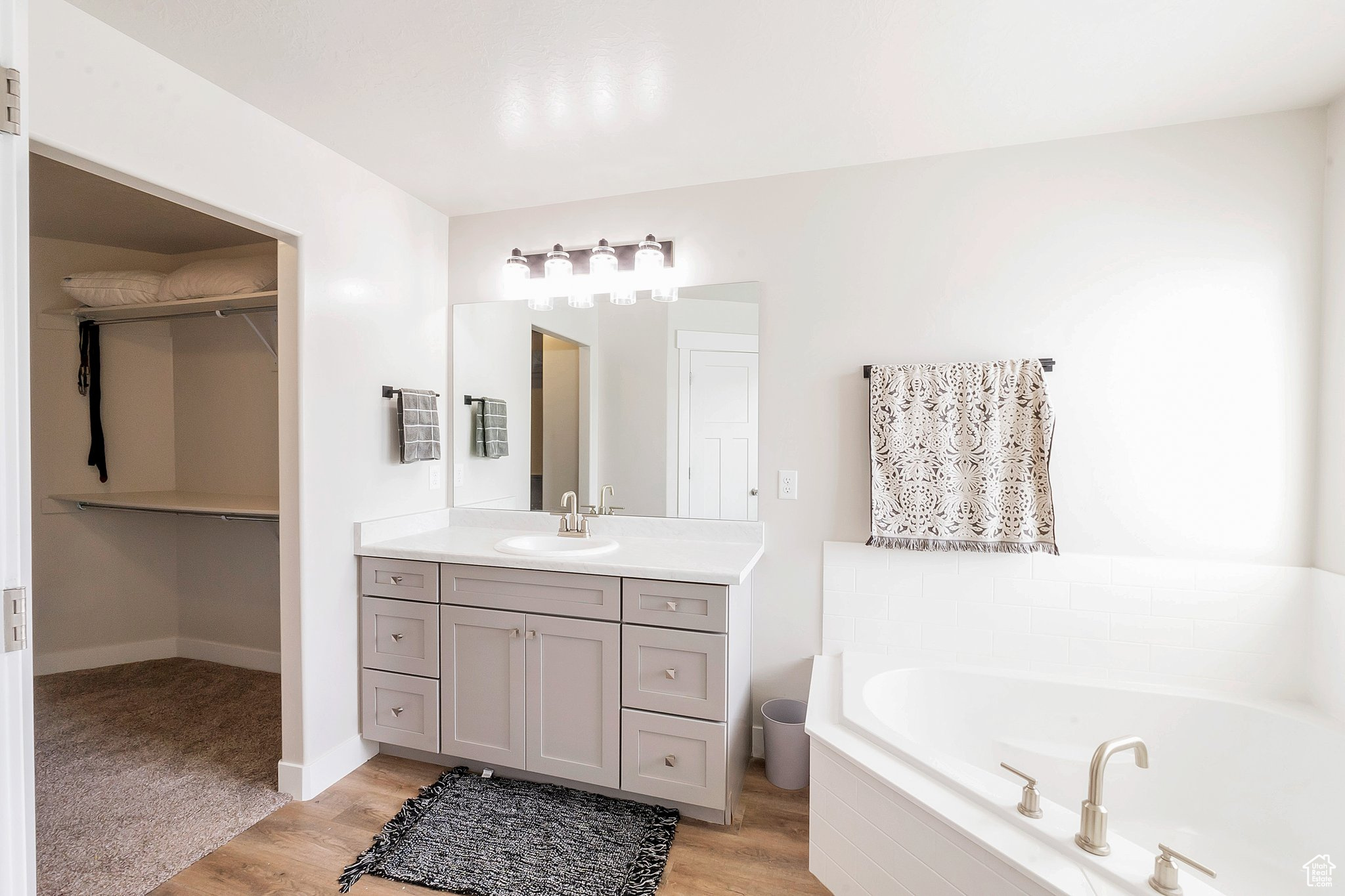 Bathroom featuring hardwood / wood-style floors, vanity, and tiled tub