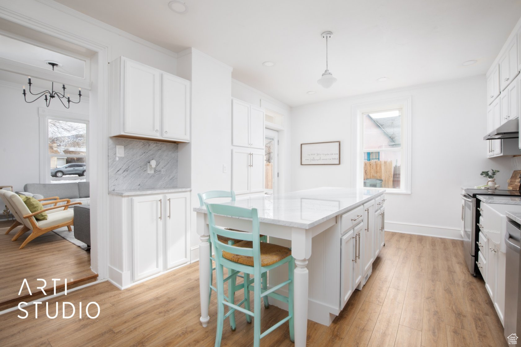 Kitchen with white cabinets, decorative light fixtures, backsplash, and light wood-type flooring