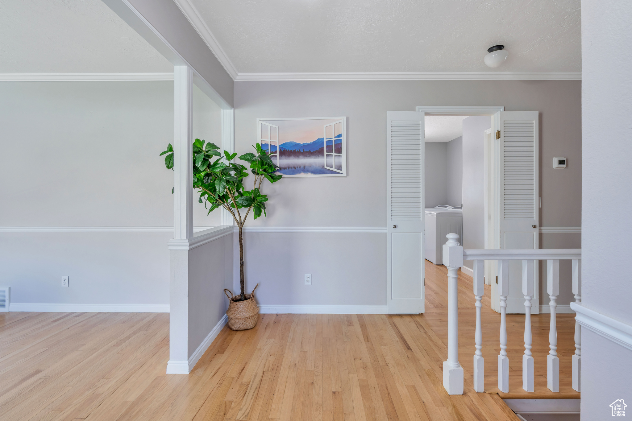 Corridor with light hardwood / wood-style floors, crown molding, and washer / clothes dryer