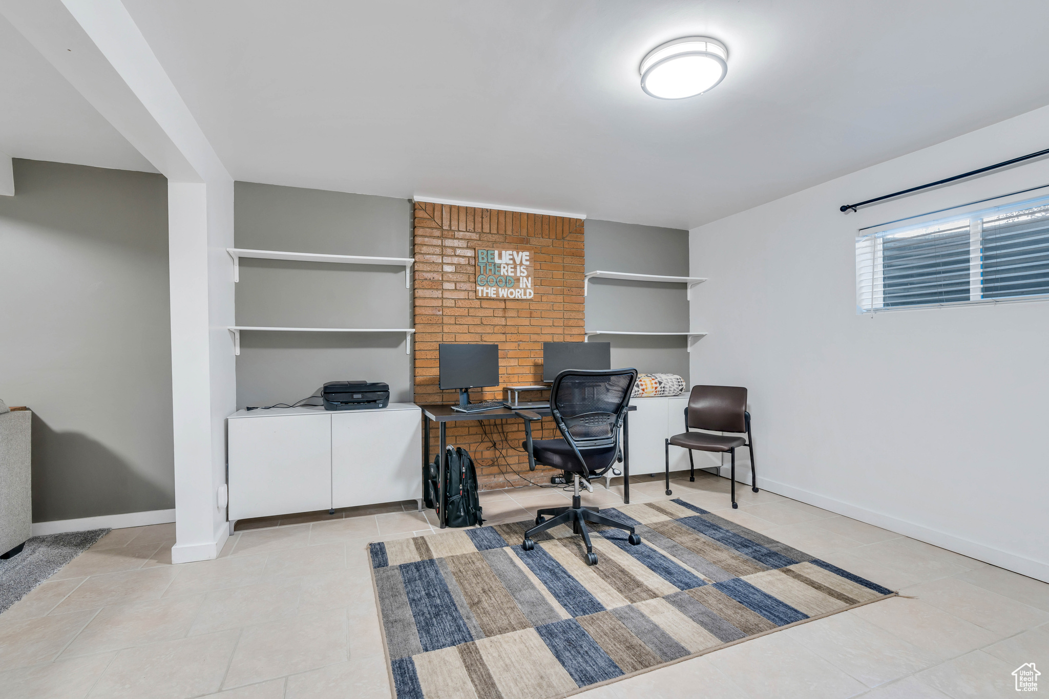 Office space featuring brick wall and light tile floors