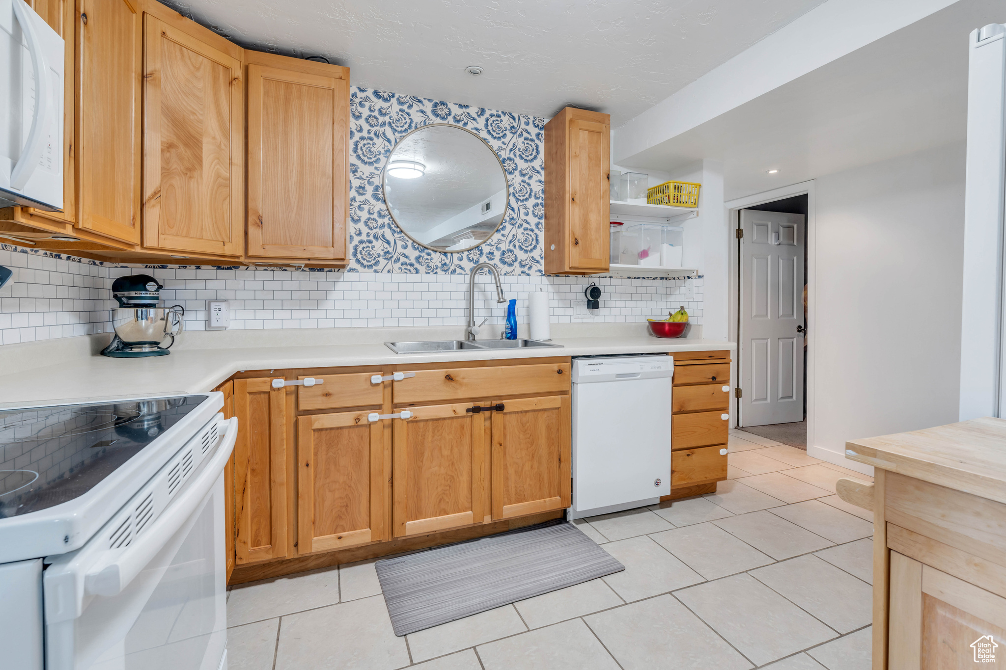 Kitchen featuring sink, white appliances, tasteful backsplash, and light tile floors