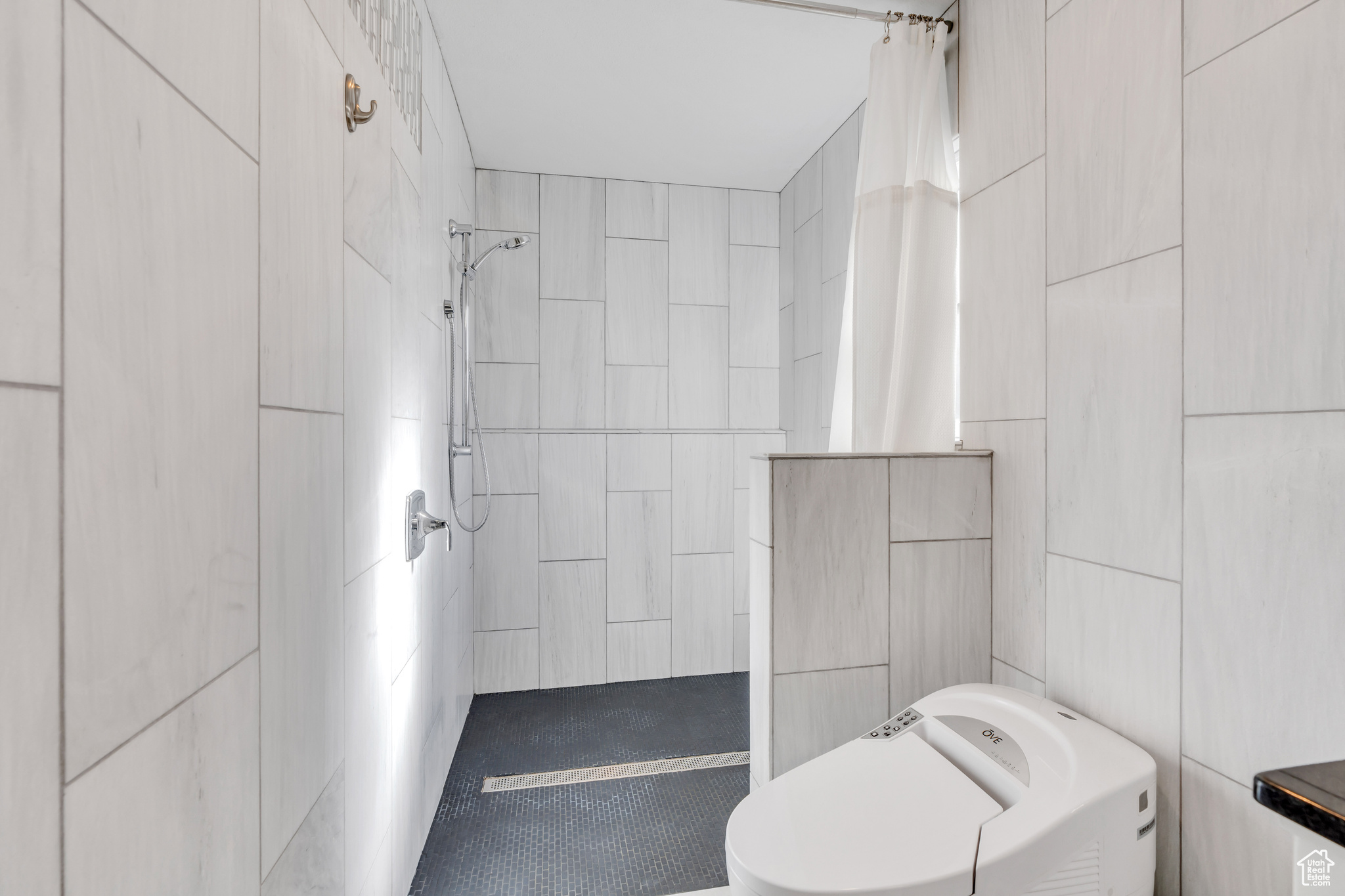 Bathroom featuring toilet, tile walls, and a shower with curtain
