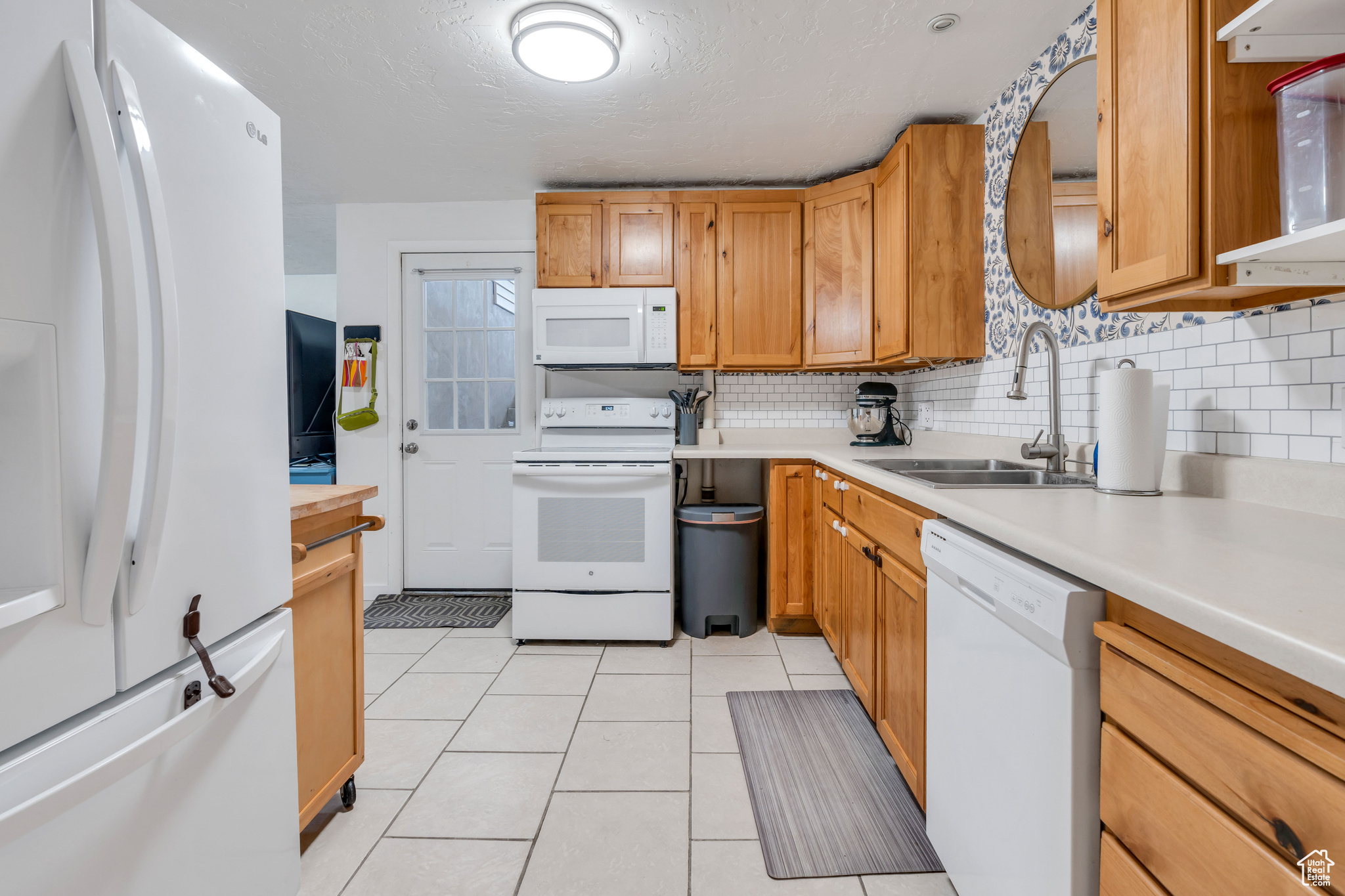 Kitchen with sink, white appliances, tasteful backsplash, and light tile floors