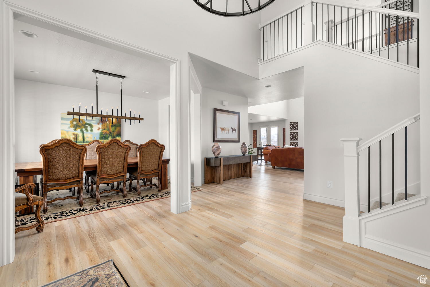 Foyer with light hardwood / wood-style flooring, an inviting custom chandelier, and a high ceiling