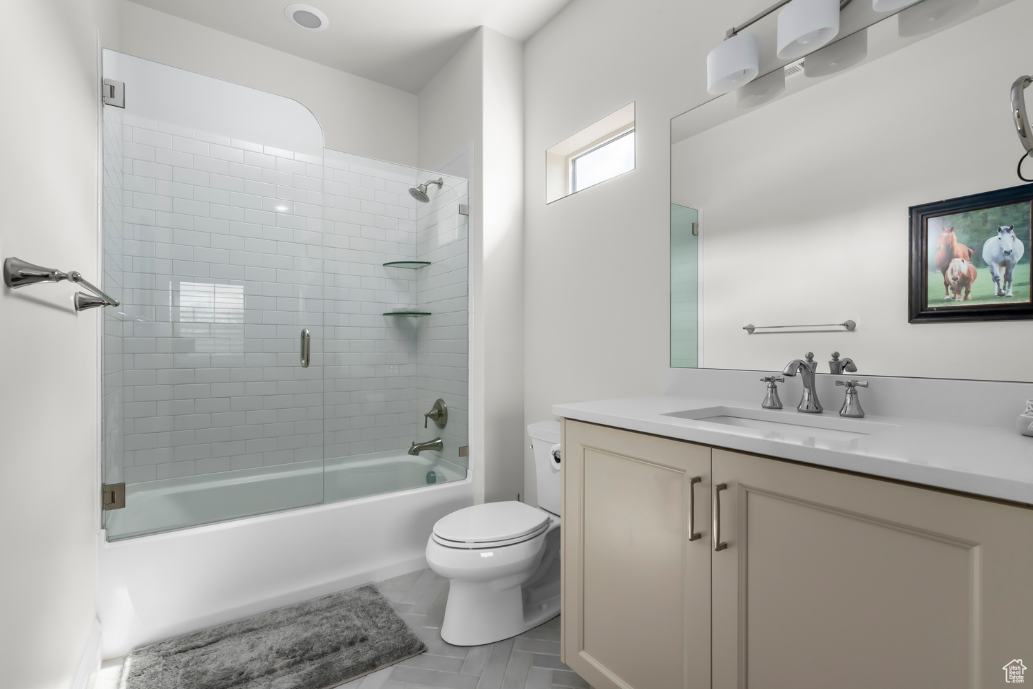 Full en suite bathroom with vanity, toilet, enclosed tub / shower combo, and tile flooring. Custom Euro glass