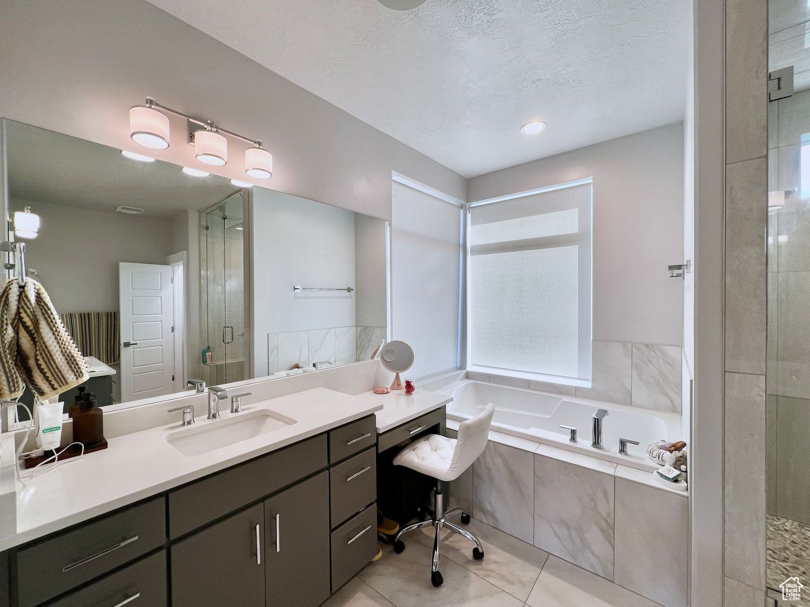 Bathroom featuring vanity, shower with separate bathtub, tile floors, and a textured ceiling