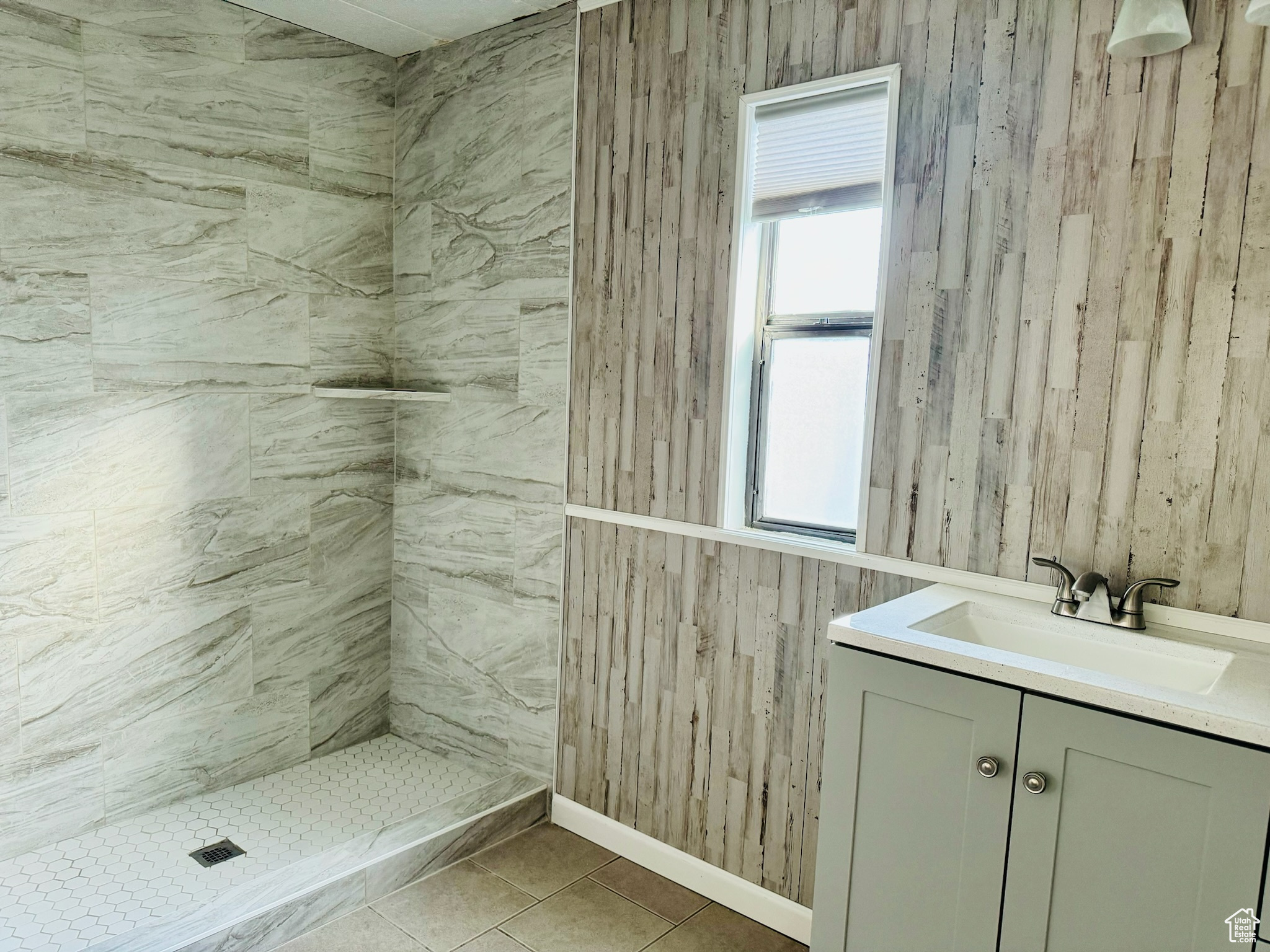 Bathroom featuring tile floors, vanity, and a tile shower