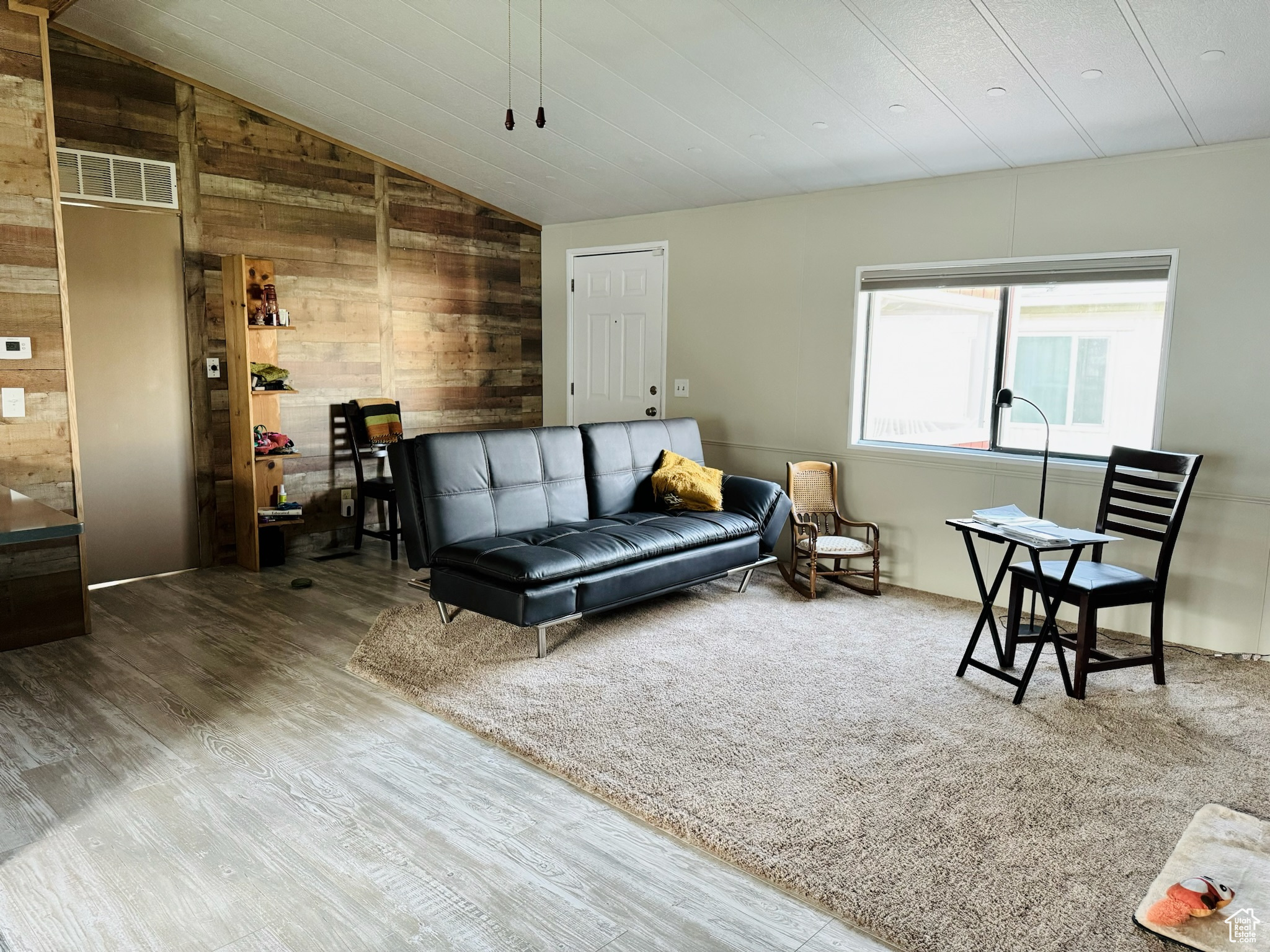 Living room with wooden walls, hardwood / wood-style floors, and lofted ceiling