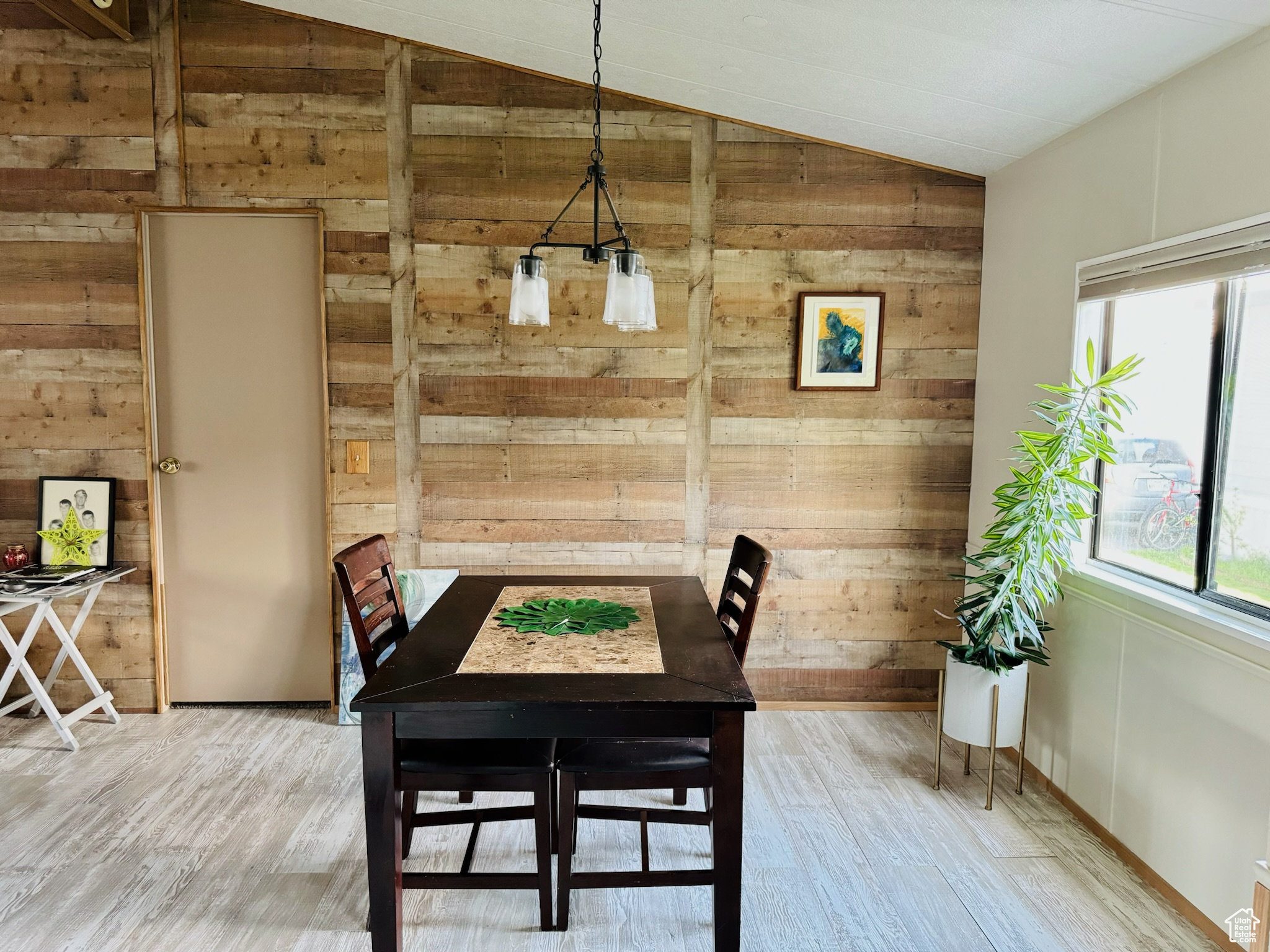 Dining room featuring lofted ceiling, wood walls, and light wood-type flooring