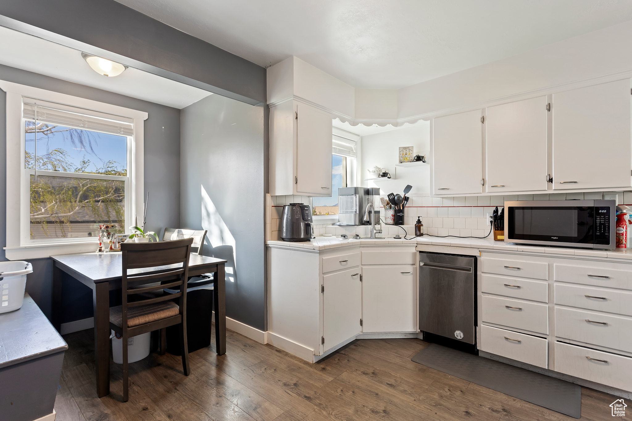 Kitchen featuring appliances with stainless steel finishes, white cabinets, tasteful backsplash, dark hardwood / wood-style flooring, and a healthy amount of sunlight