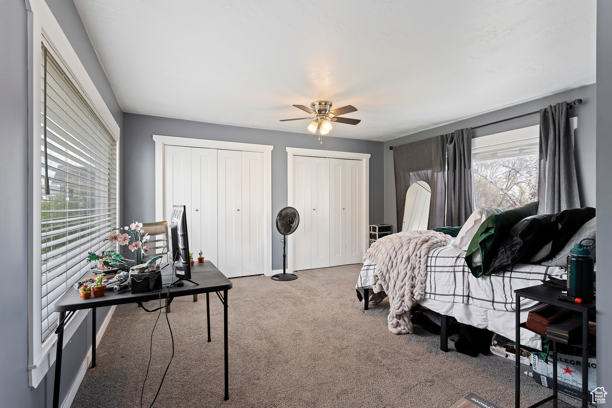 Bedroom featuring ceiling fan, dark carpet, and two closets