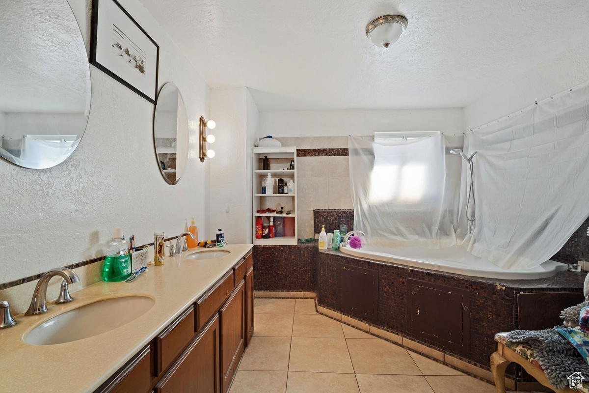 Bathroom featuring dual bowl vanity, a textured ceiling, and tile flooring