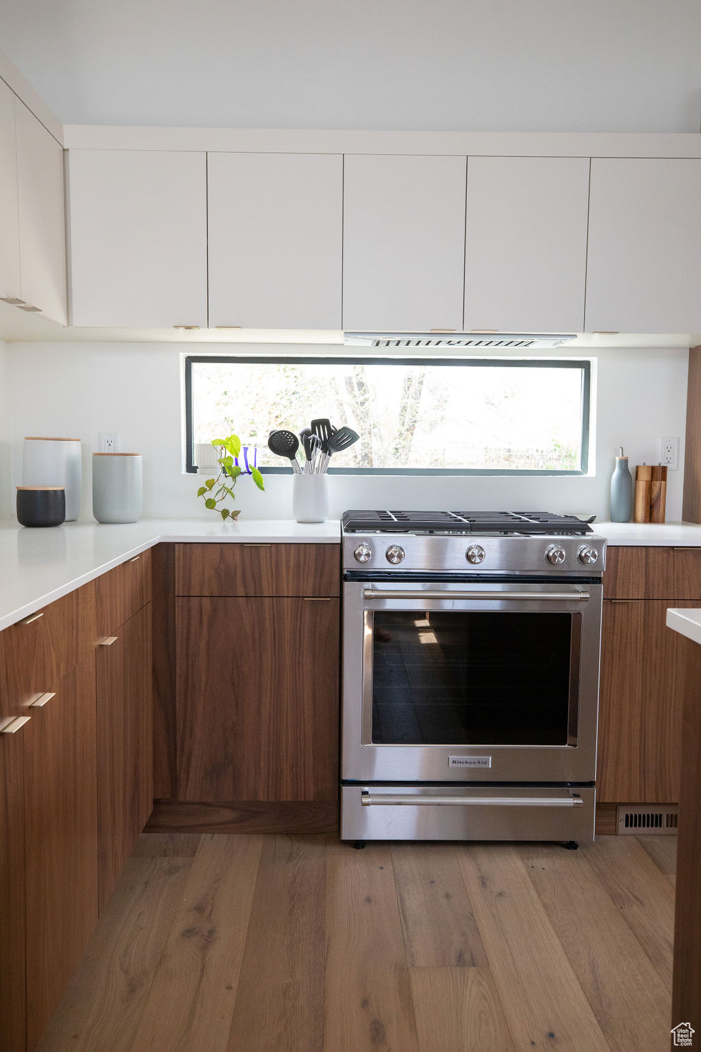 Kitchen with stainless steel stove, wood-type flooring, and white cabinets
