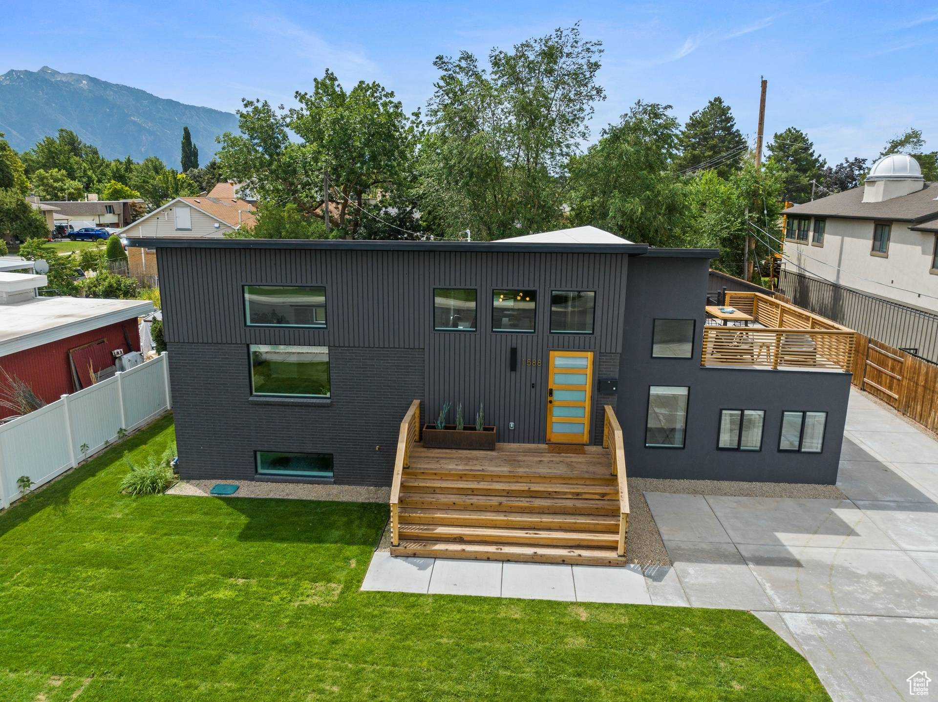 Contemporary home featuring a front lawn, a mountain view, and a patio