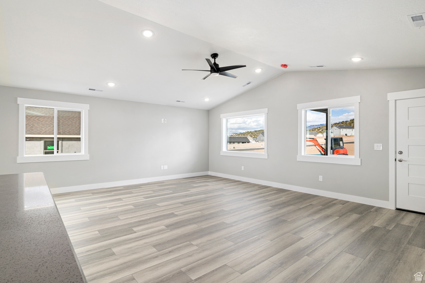 Empty room with vaulted ceiling, light hardwood / wood-style flooring, and ceiling fan