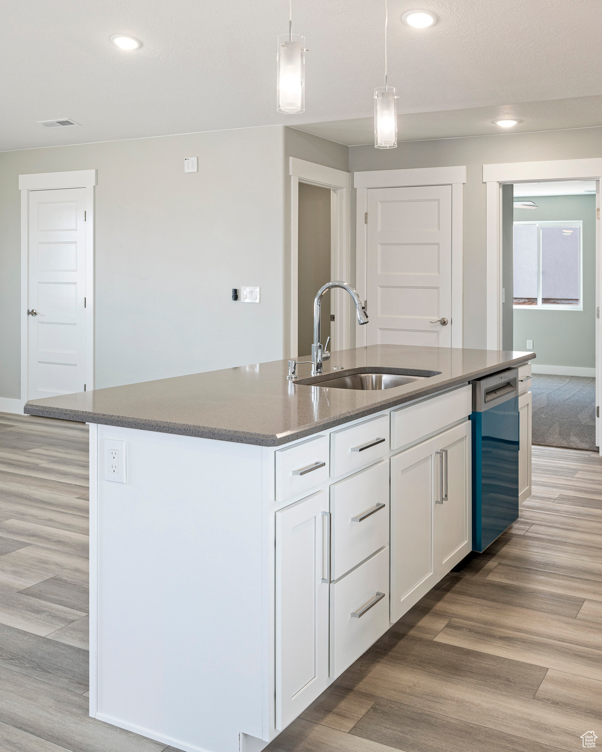 Kitchen featuring sink, light hardwood / wood-style floors, stainless steel dishwasher, and a kitchen island with sink