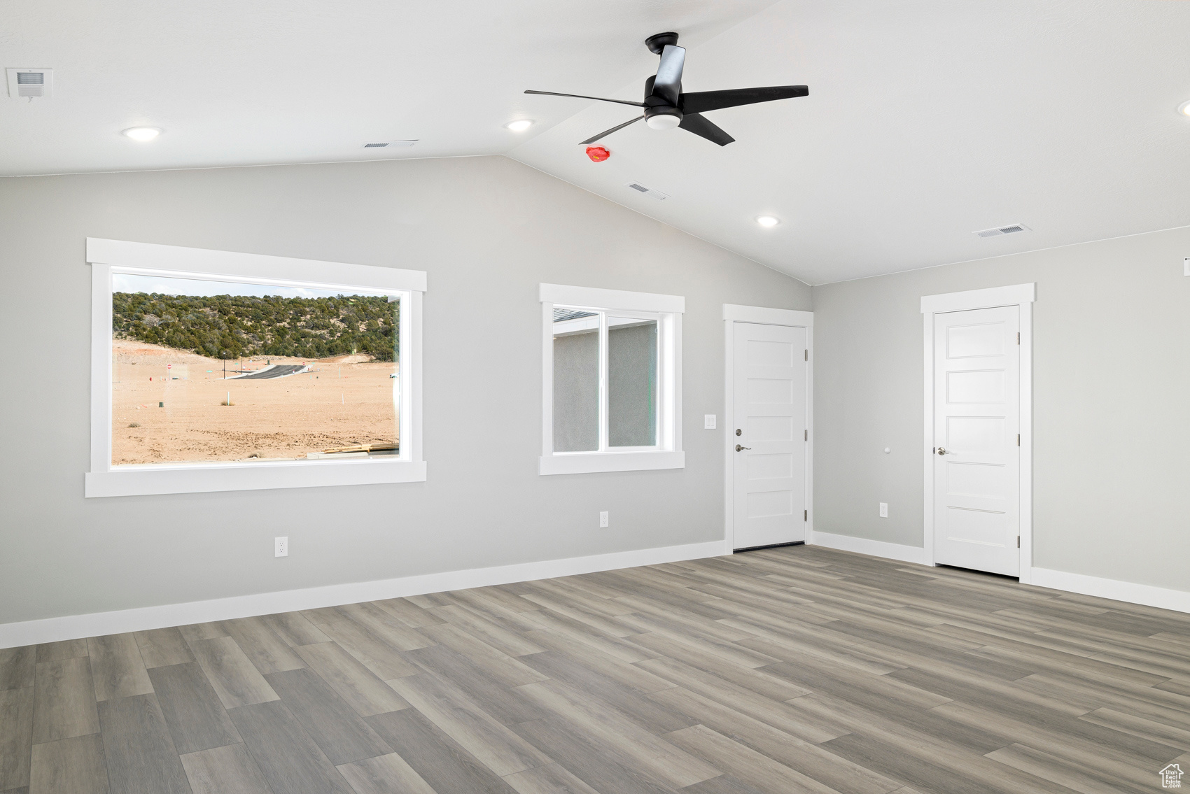 Empty room featuring hardwood / wood-style floors, lofted ceiling, and ceiling fan