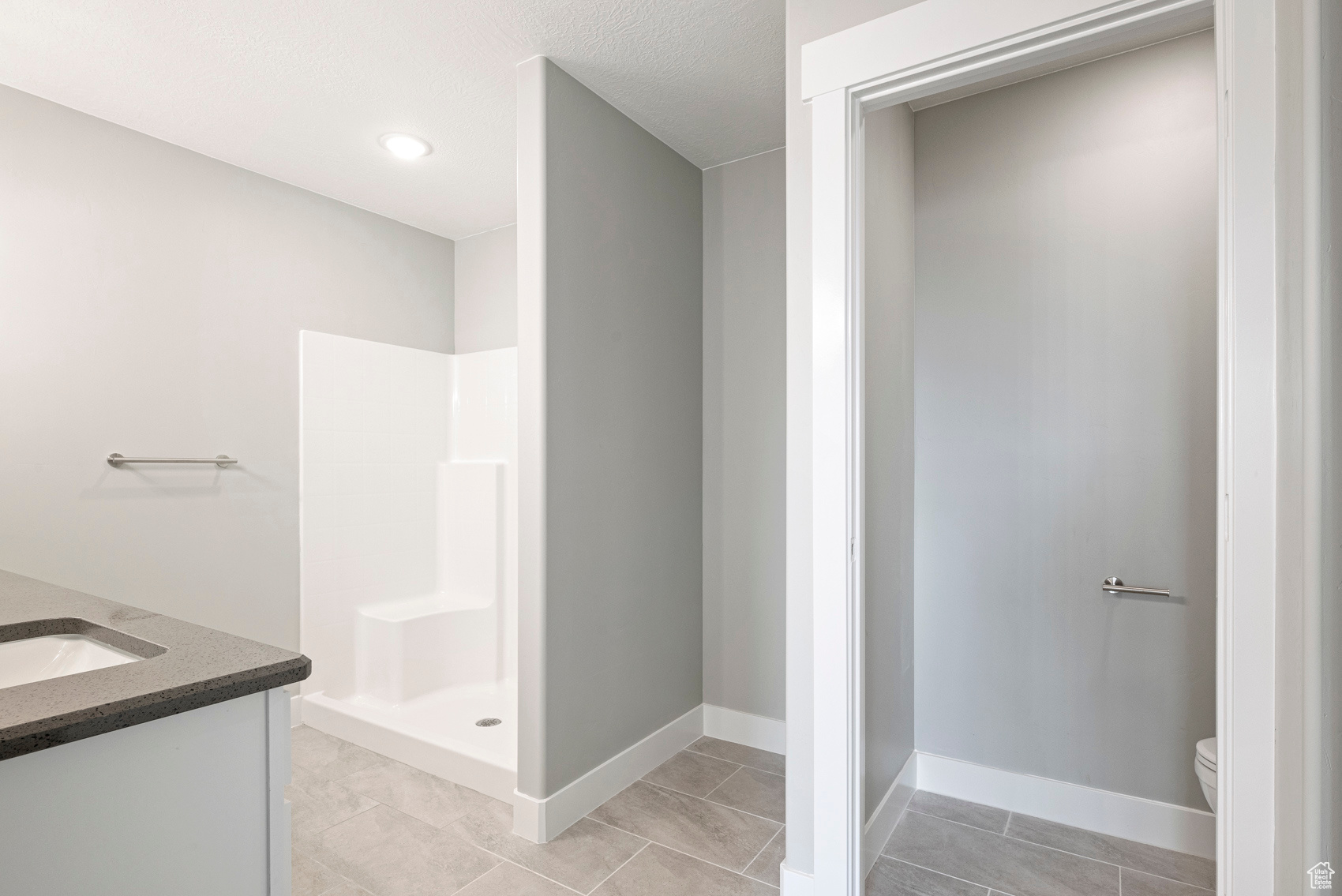 Bathroom featuring tile flooring, walk in shower, vanity, and toilet