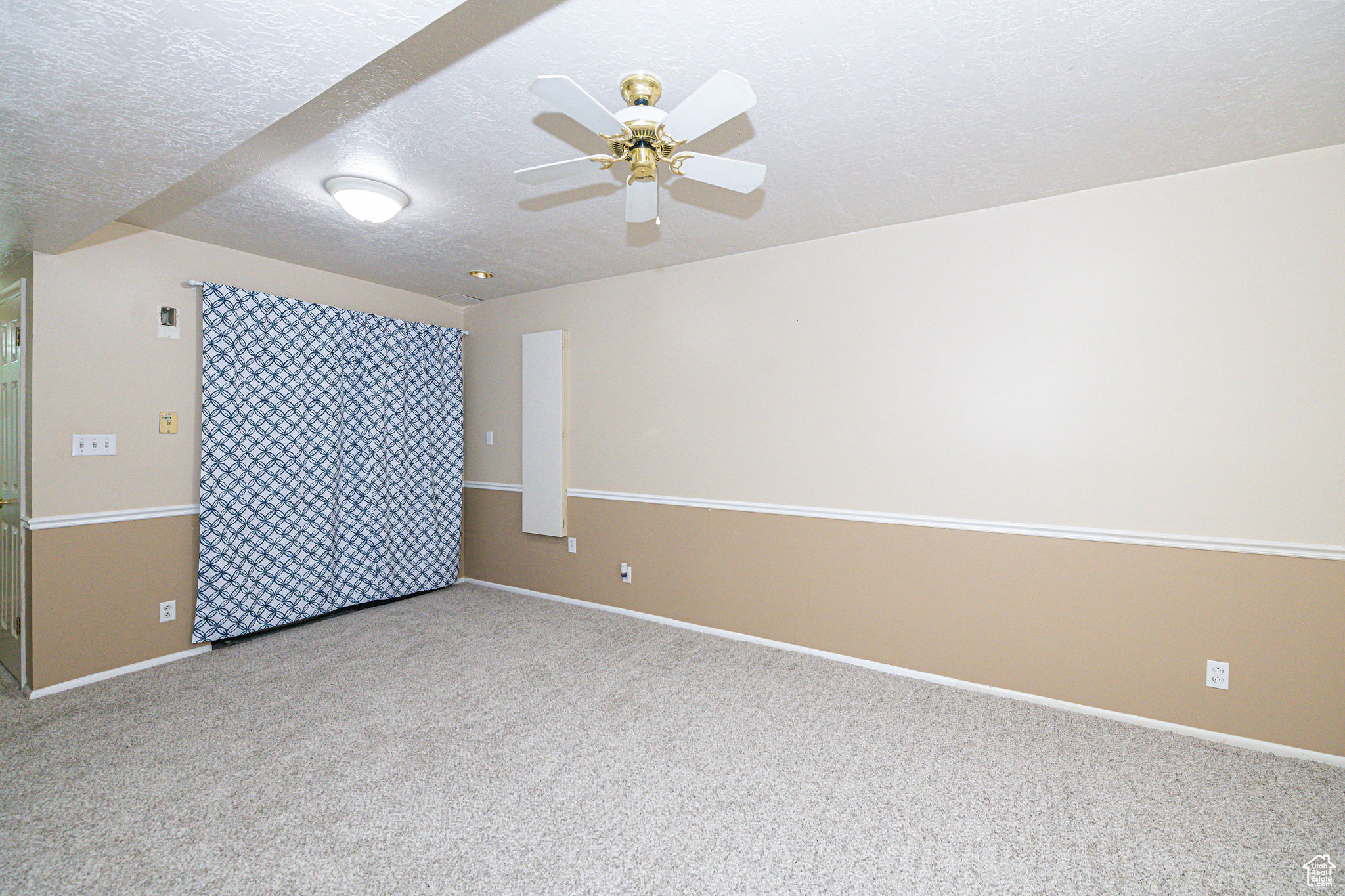 Spare room with a textured ceiling, ceiling fan, and light carpet
