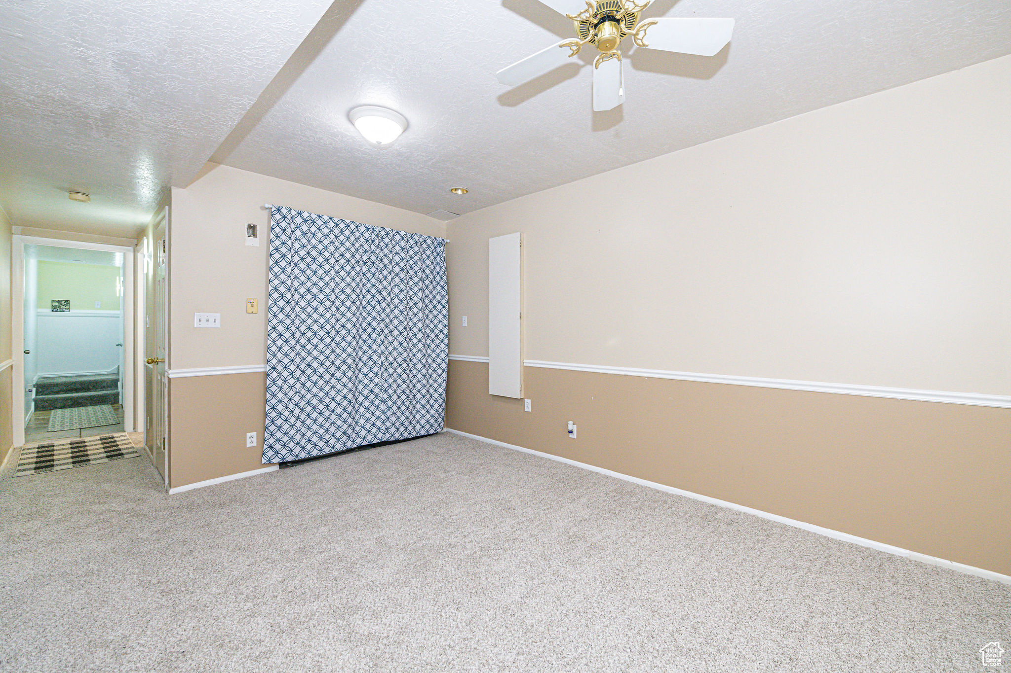 Carpeted spare room featuring a textured ceiling and ceiling fan