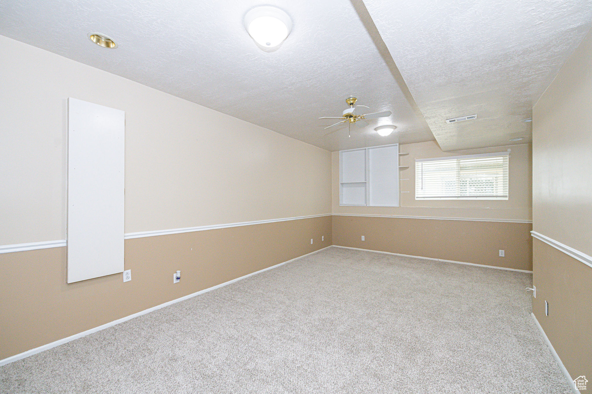 Unfurnished room featuring light carpet, ceiling fan, and a textured ceiling