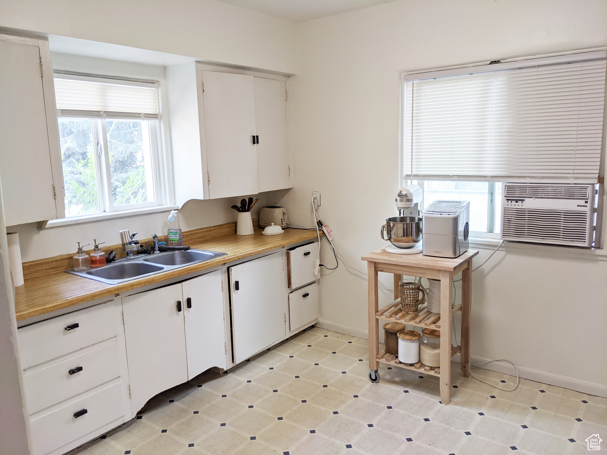 Kitchen featuring sink, white cabinetry, and light tile floors