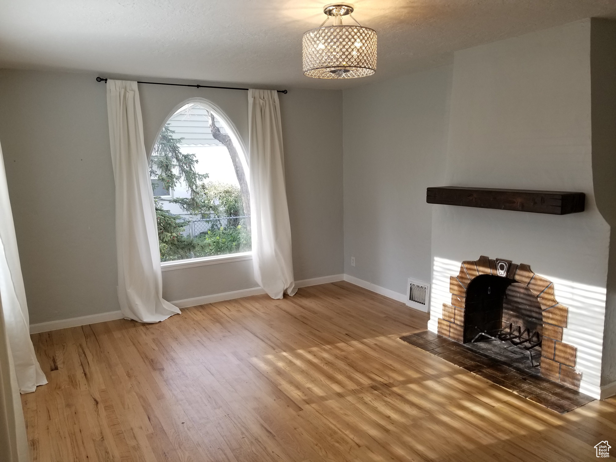 Unfurnished living room with a brick fireplace and light wood-type flooring