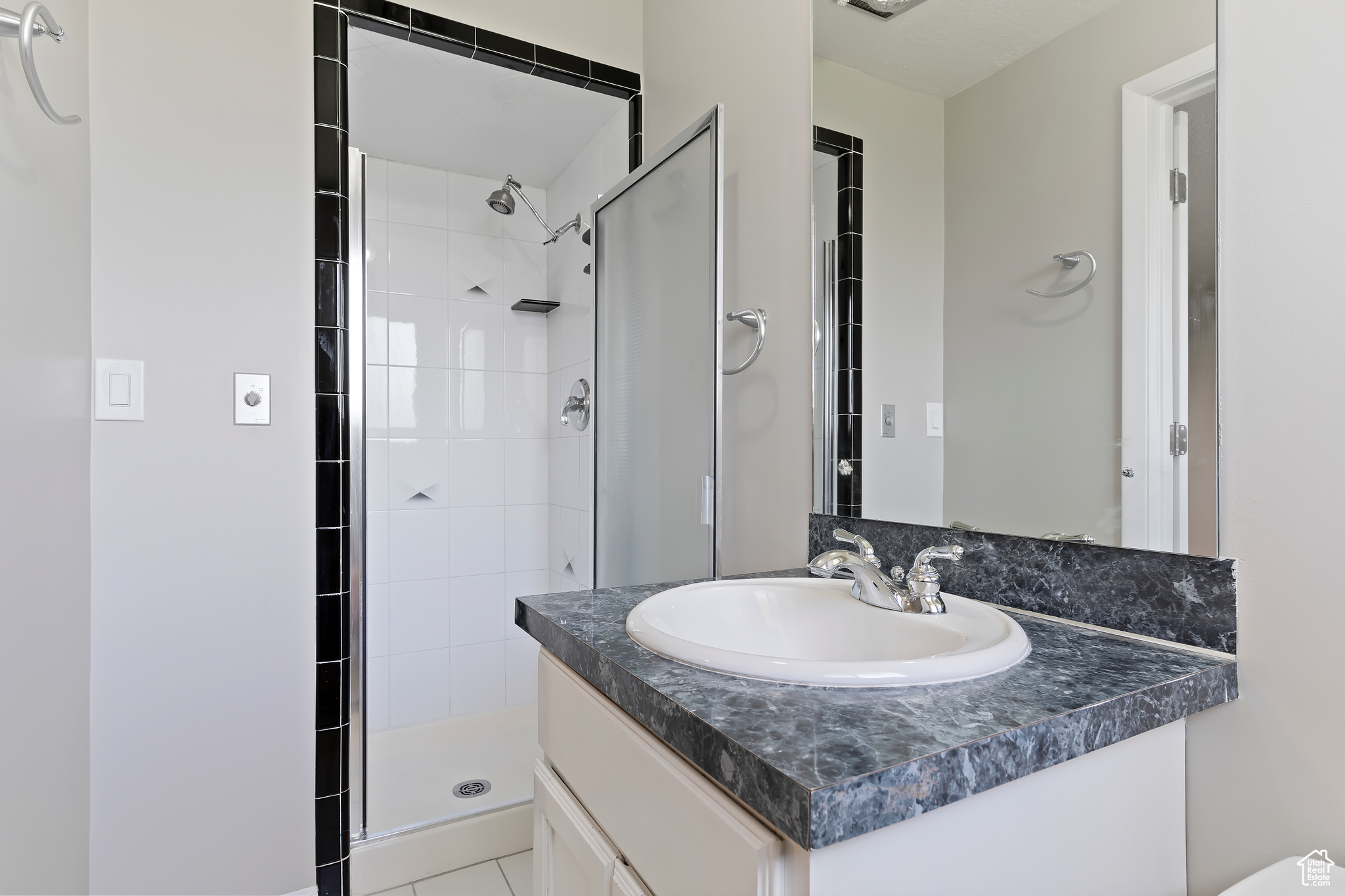 Bathroom featuring tile flooring, oversized vanity, and a shower with door