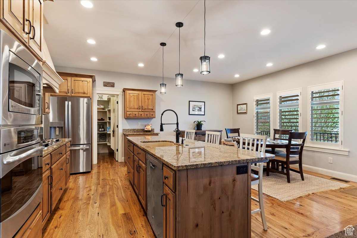 Kitchen featuring a kitchen bar, stainless steel appliances, hardwood floors, an island with sink