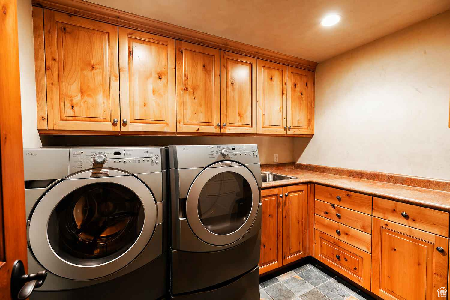 Clothes washing area featuring cabinets, light tile floors, and washer and dryer
