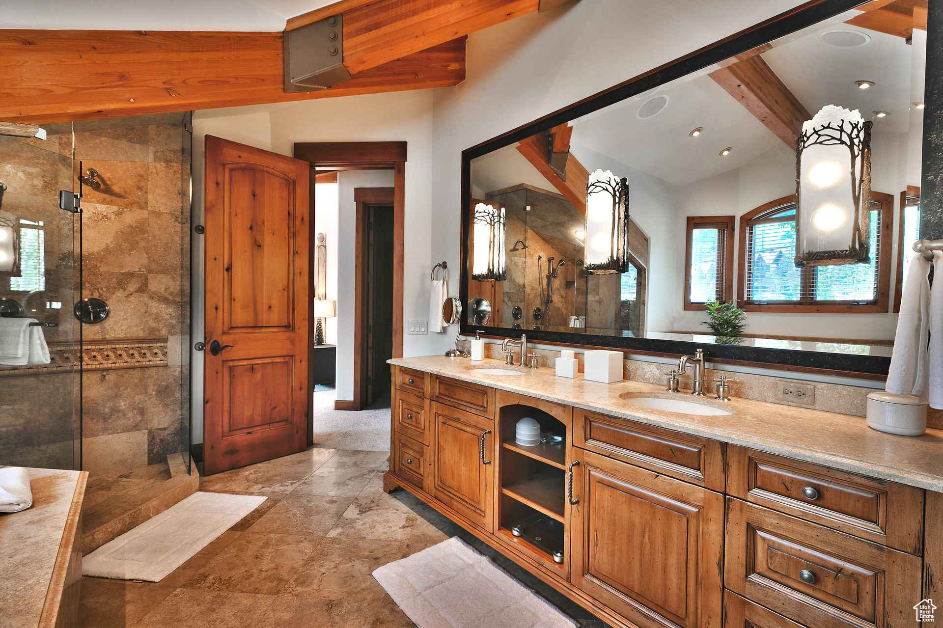 Bathroom with lofted ceiling with beams, tile floors, tiled shower, and double sink vanity