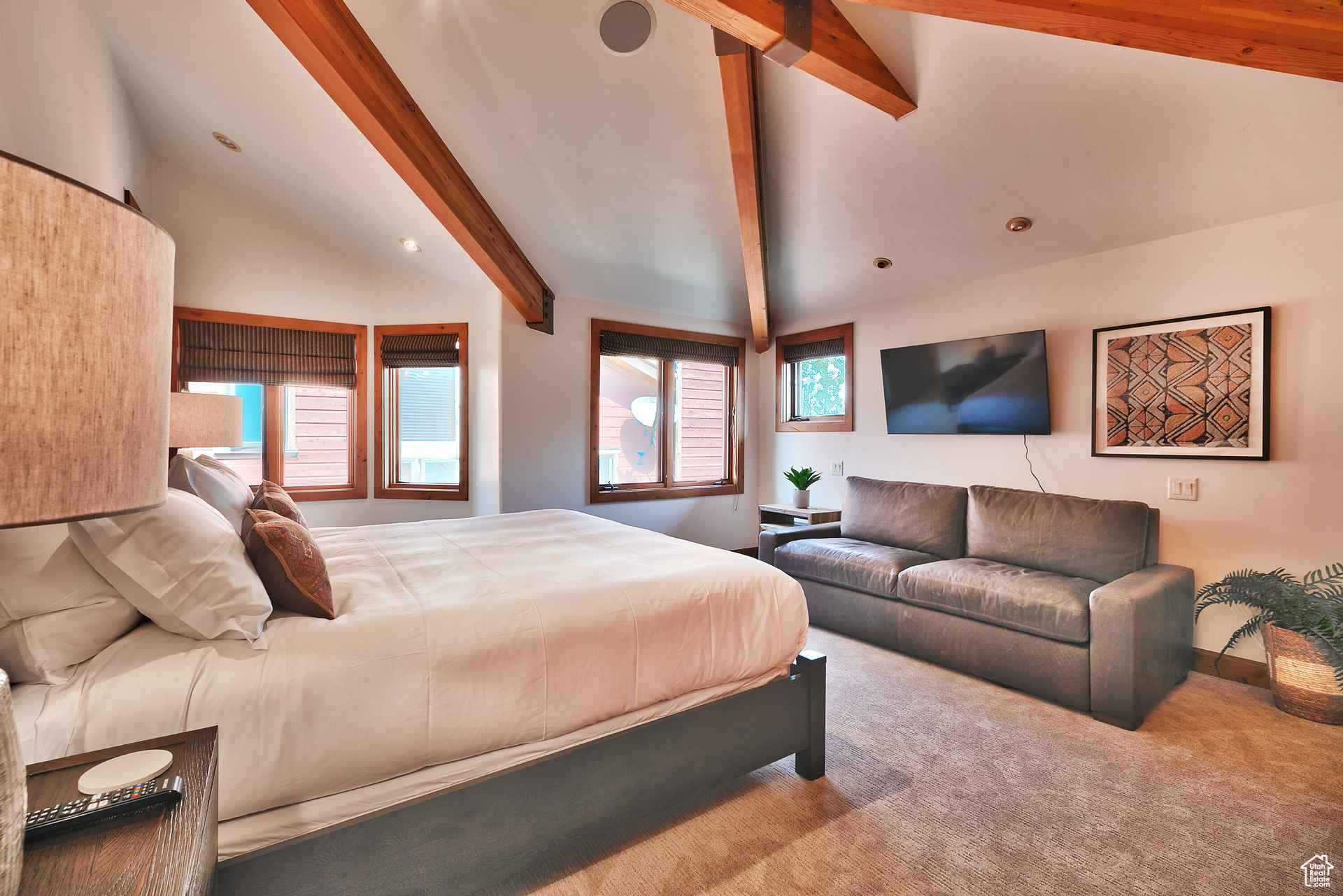 Carpeted bedroom featuring vaulted ceiling with beams and multiple windows