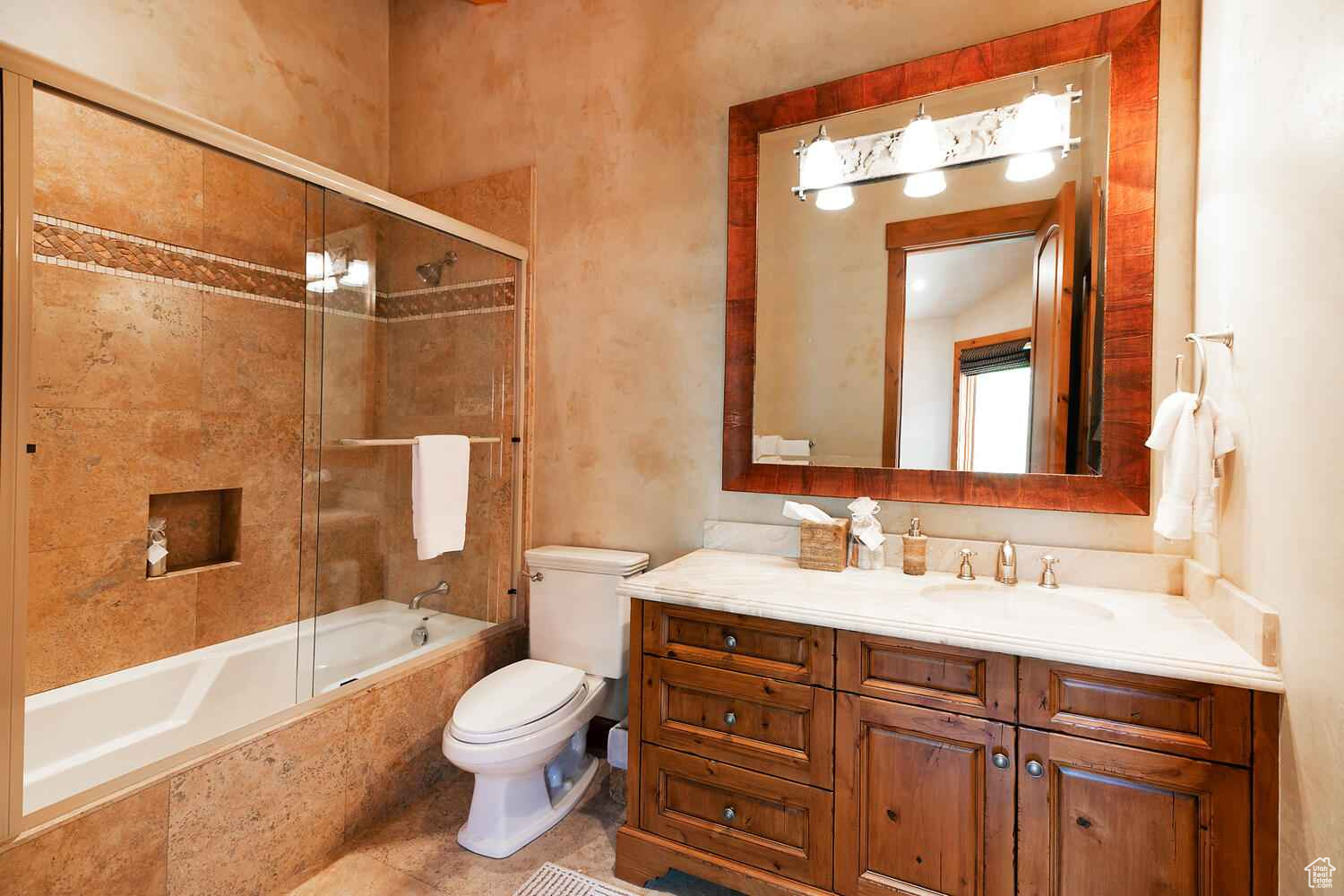 Full bathroom with oversized vanity, shower / bath combination with glass door, tile floors, and toilet