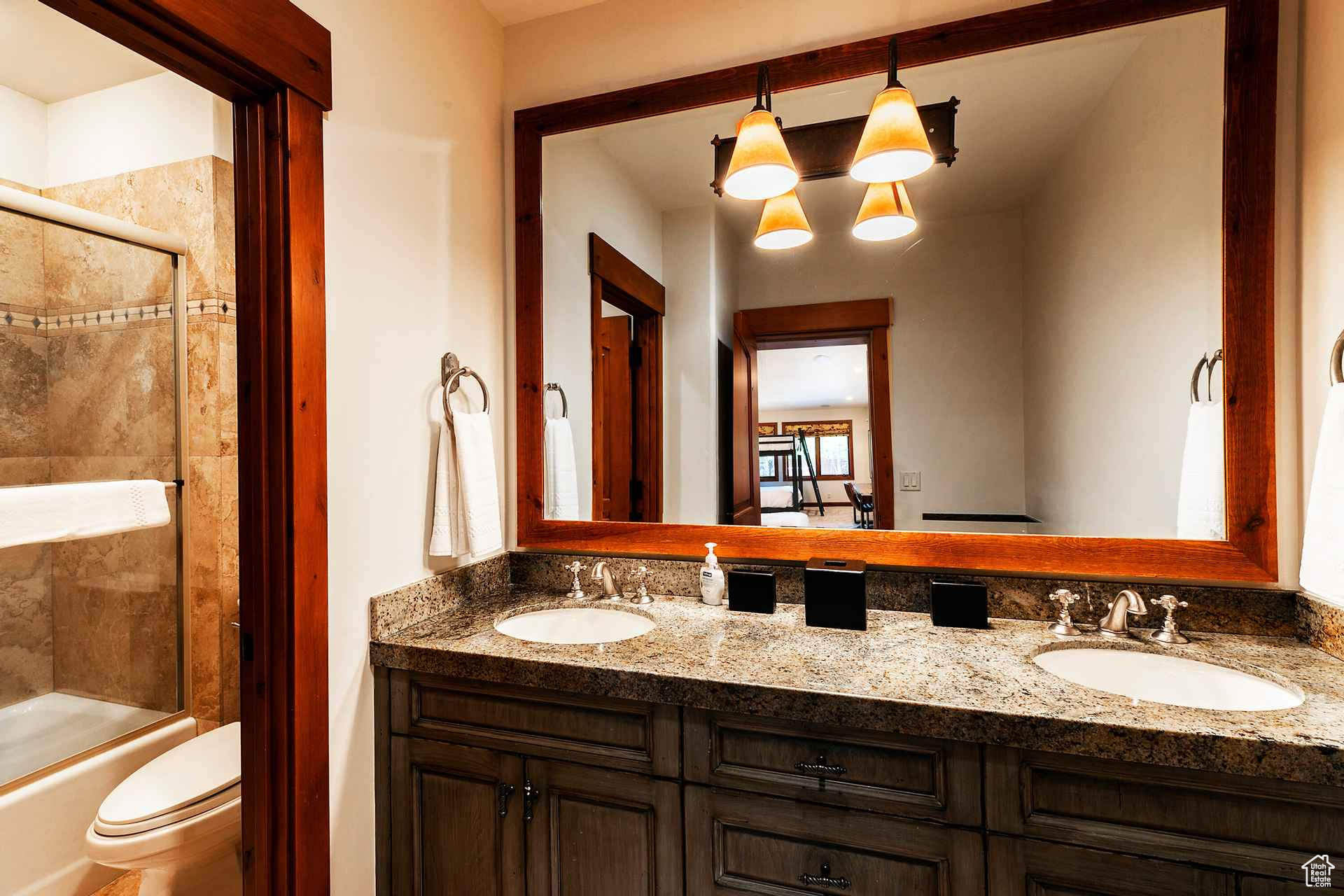 Full bathroom featuring oversized vanity, shower / bath combination with glass door, toilet, and double sink