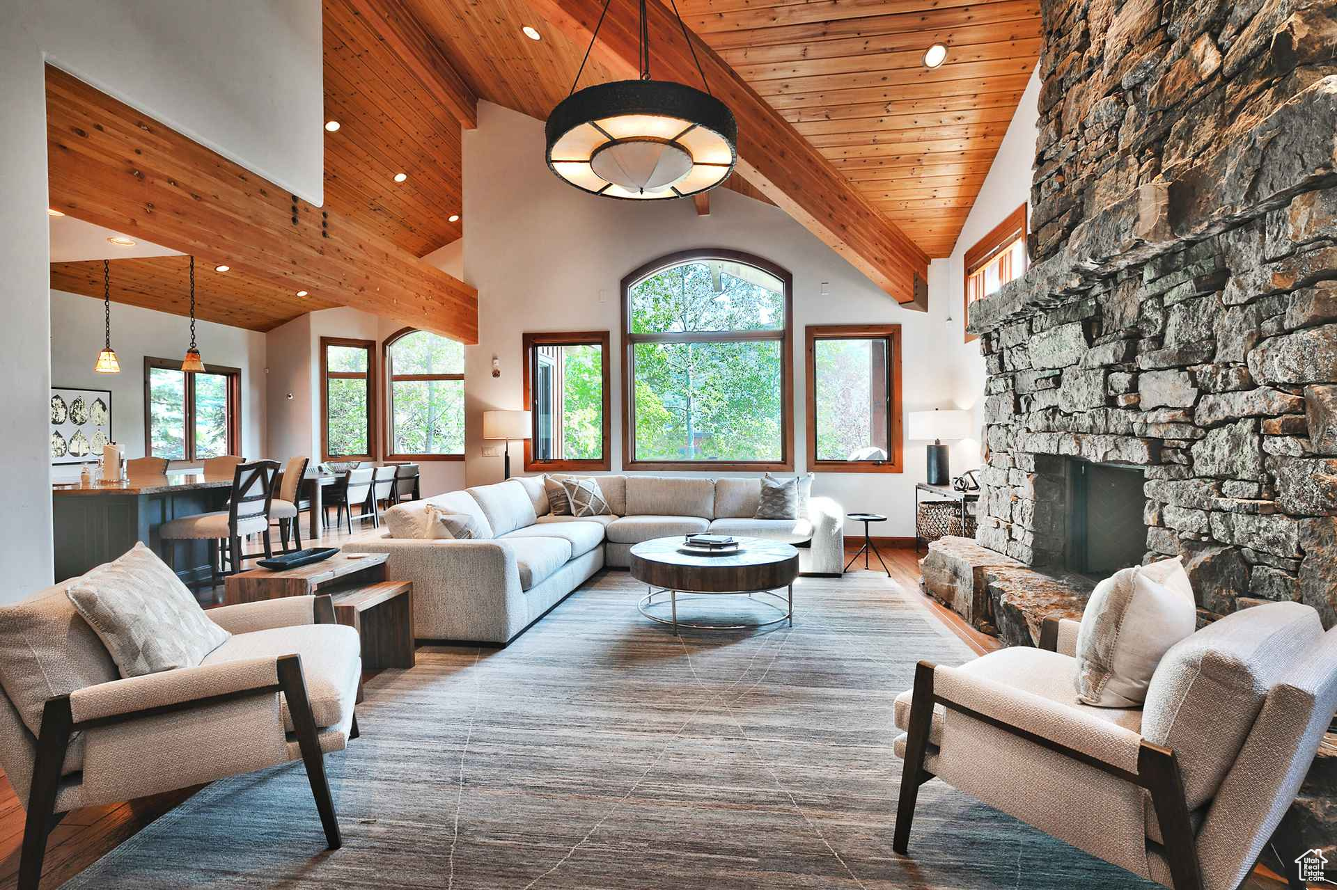 Living room featuring high vaulted ceiling, dark hardwood / wood-style flooring, wooden ceiling, beam ceiling, and a stone fireplace