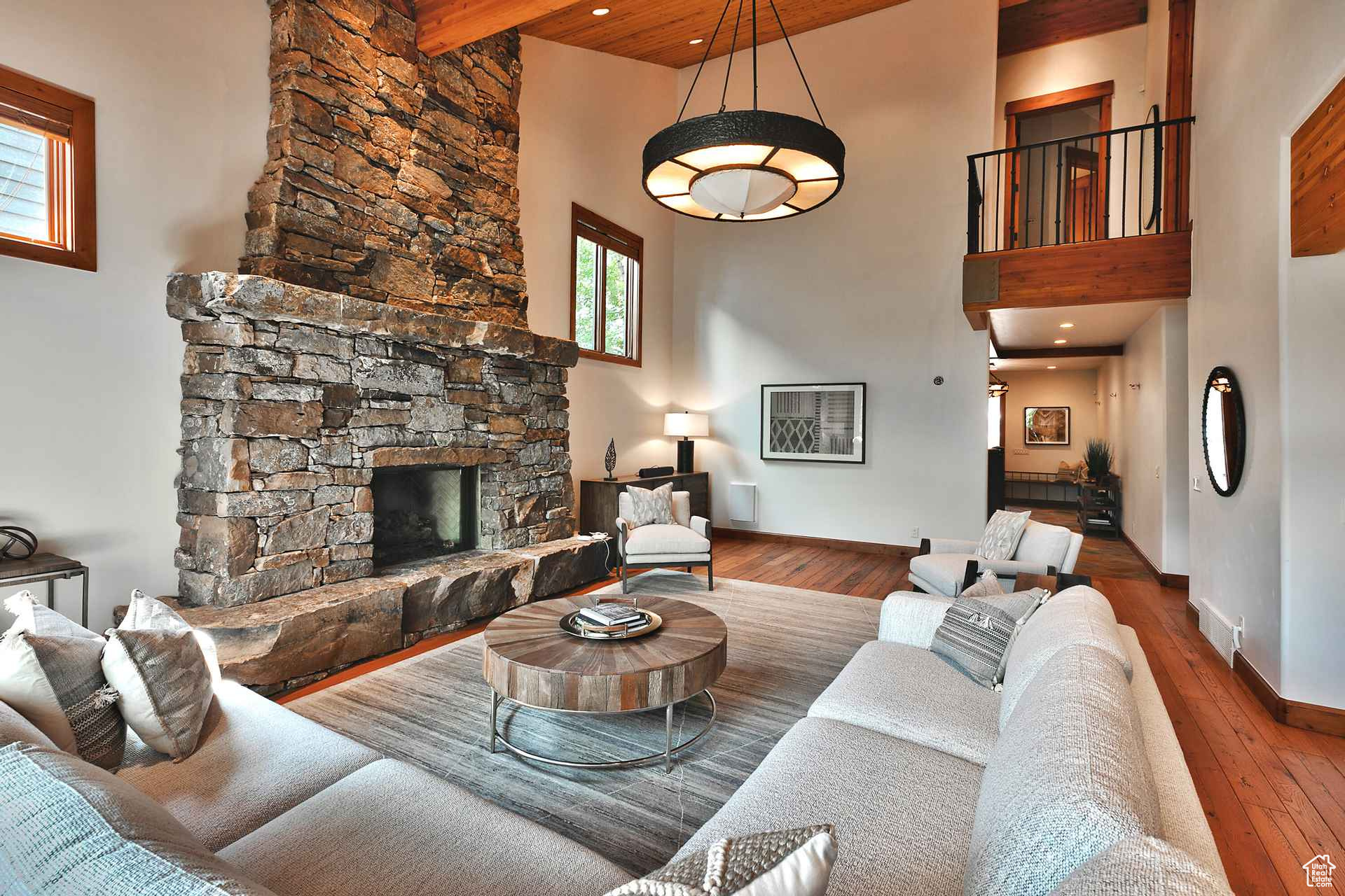 Living room featuring a high ceiling, beam ceiling, a stone fireplace, and dark hardwood / wood-style floors