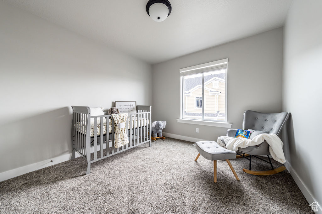 Bedroom with vaulted ceiling, light carpet, and a nursery area