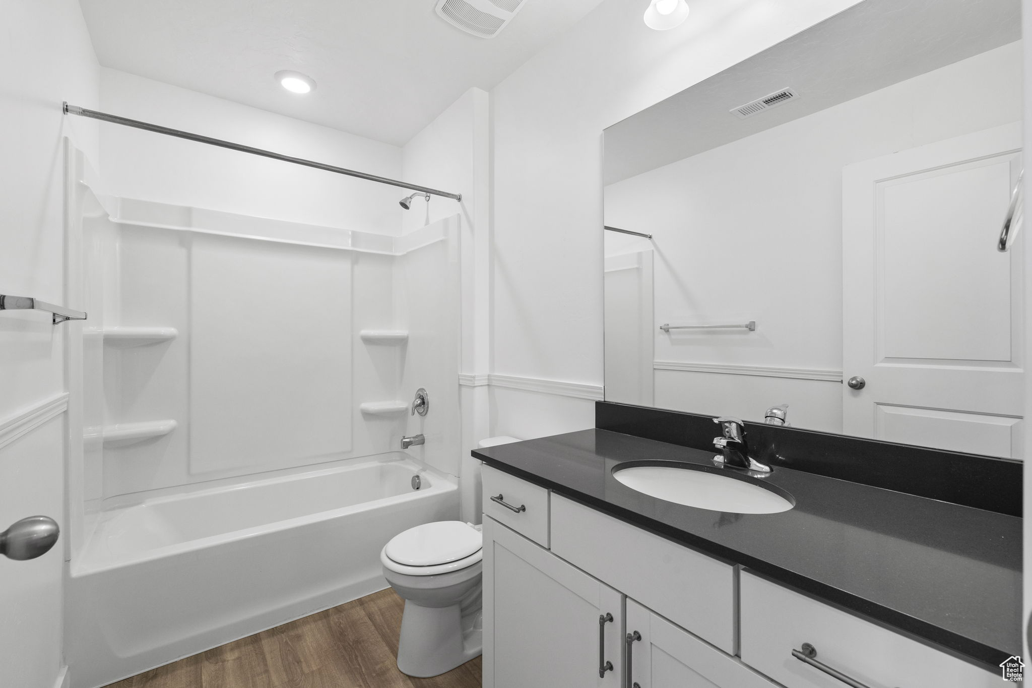Full bathroom with shower / bathing tub combination, vanity, hardwood / wood-style flooring, and toilet